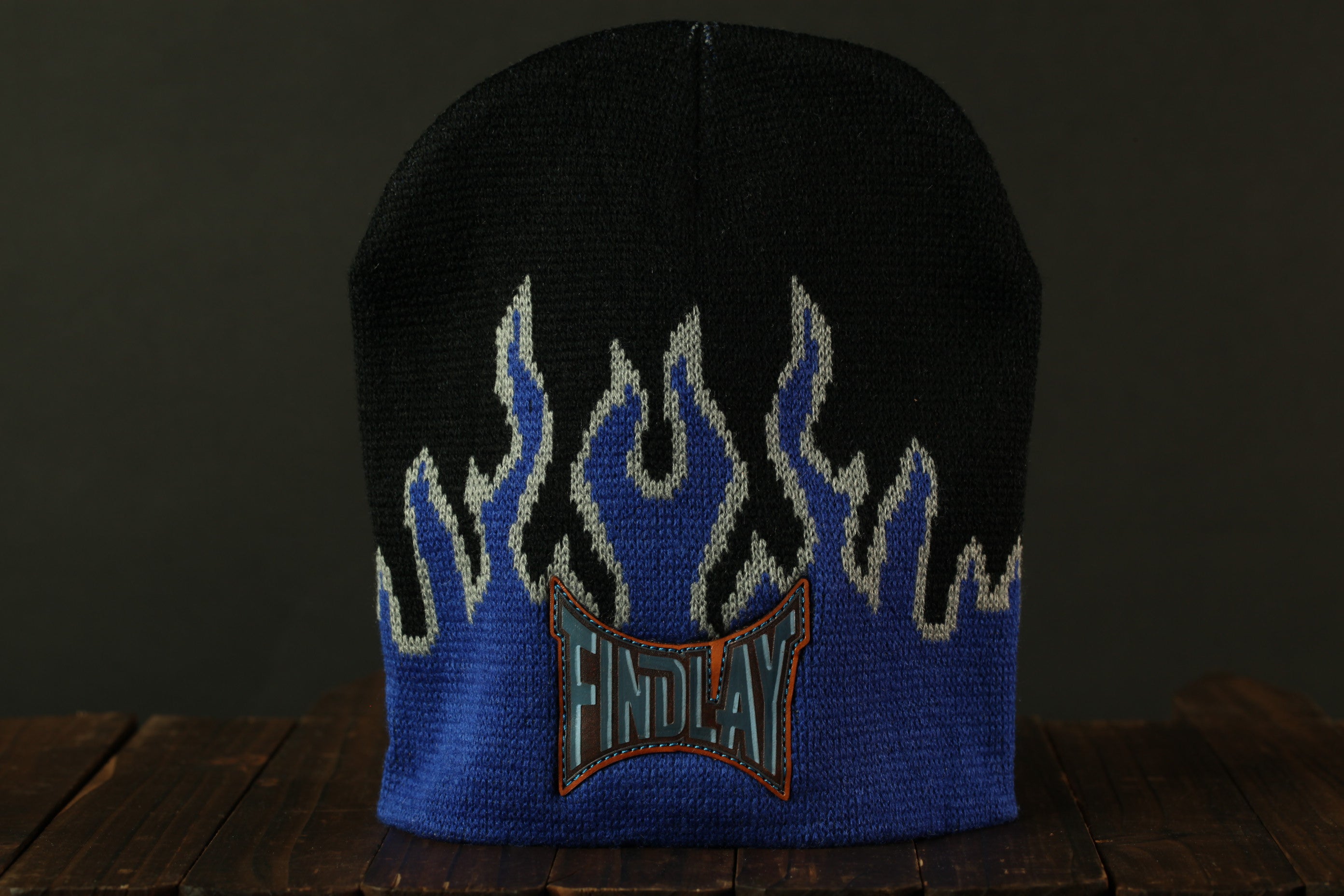 A black and blue knit beanie with a flame design on the front, featuring the word "FINDlay" on the front edge.