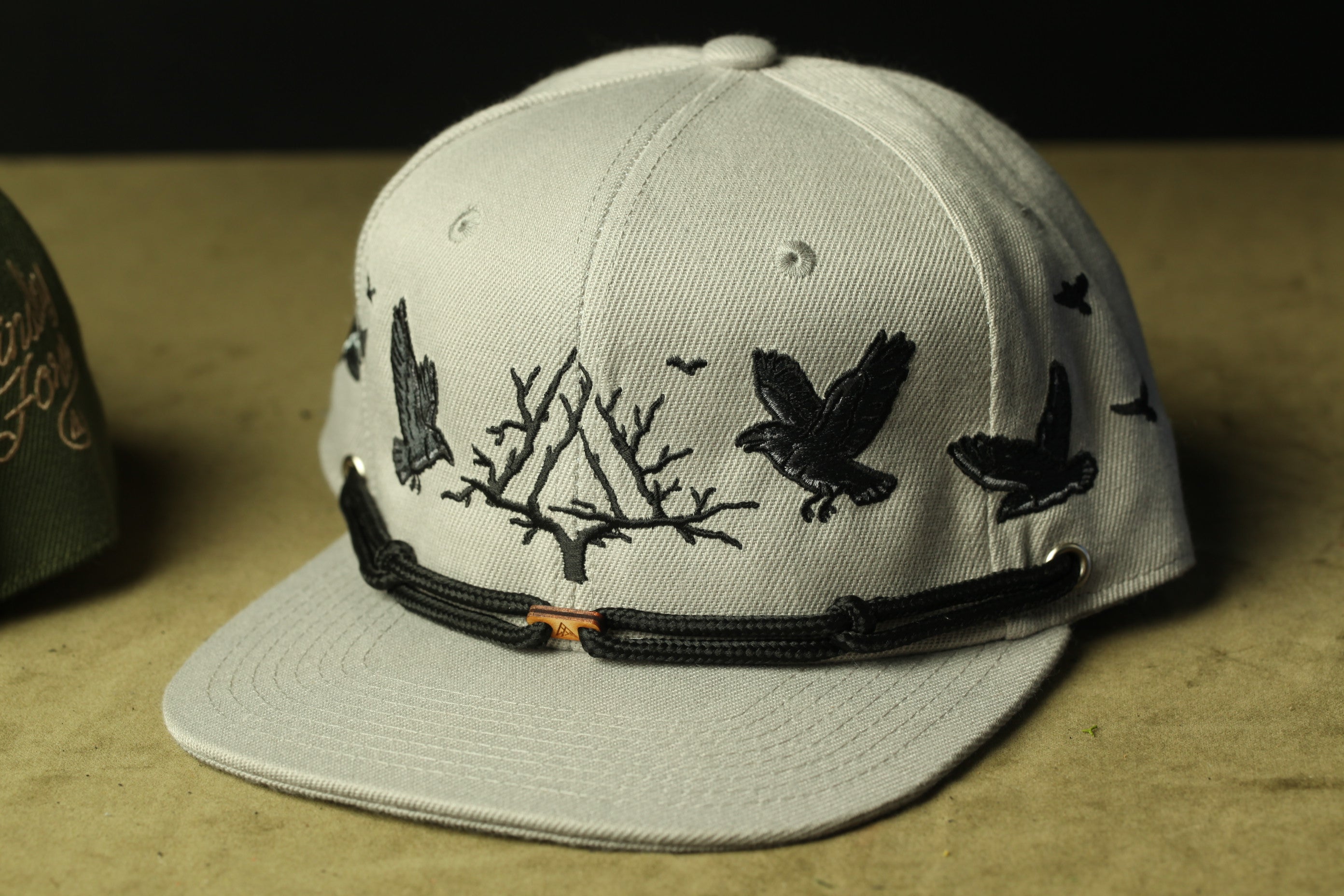 A white baseball cap with black bird embroidery on the front.