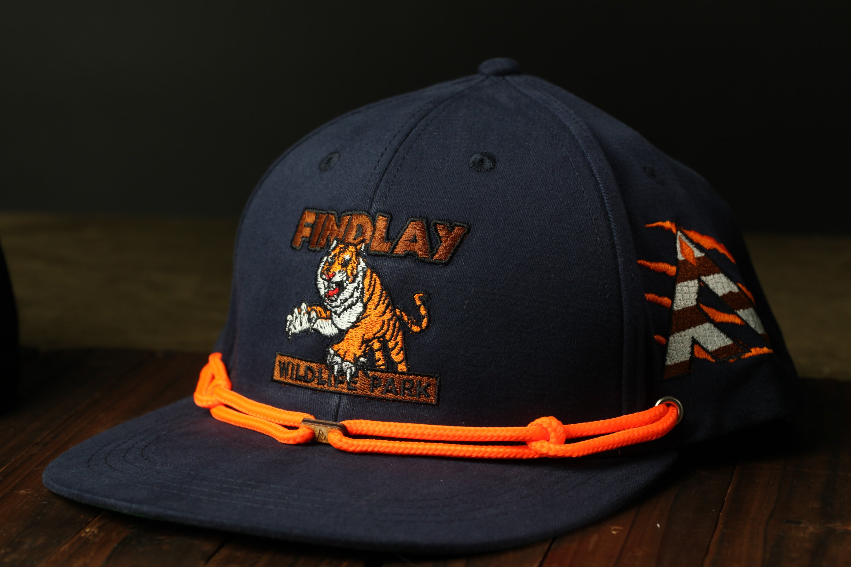A navy blue baseball cap with an orange and white tiger logo, a "Findlay" brand name, and the text "Wildlife Park" printed on it.