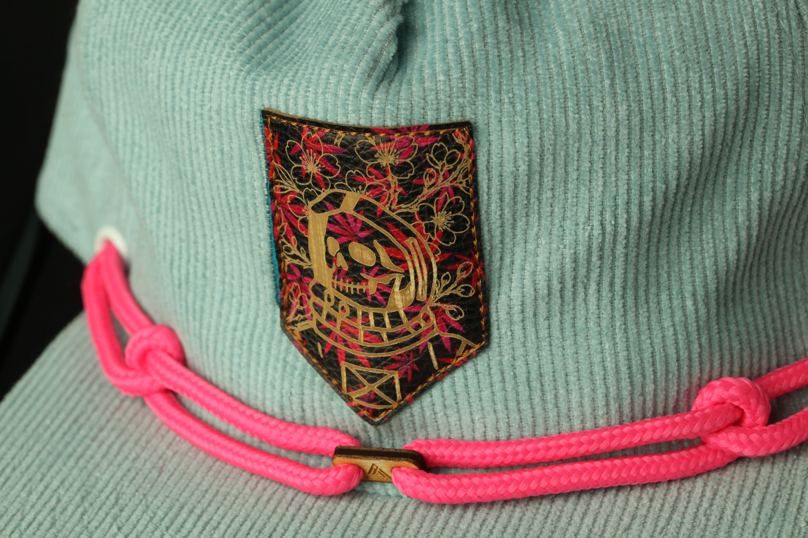 A close-up view of a light blue knitted hat with a decorative patch featuring a skull design and floral patterns.