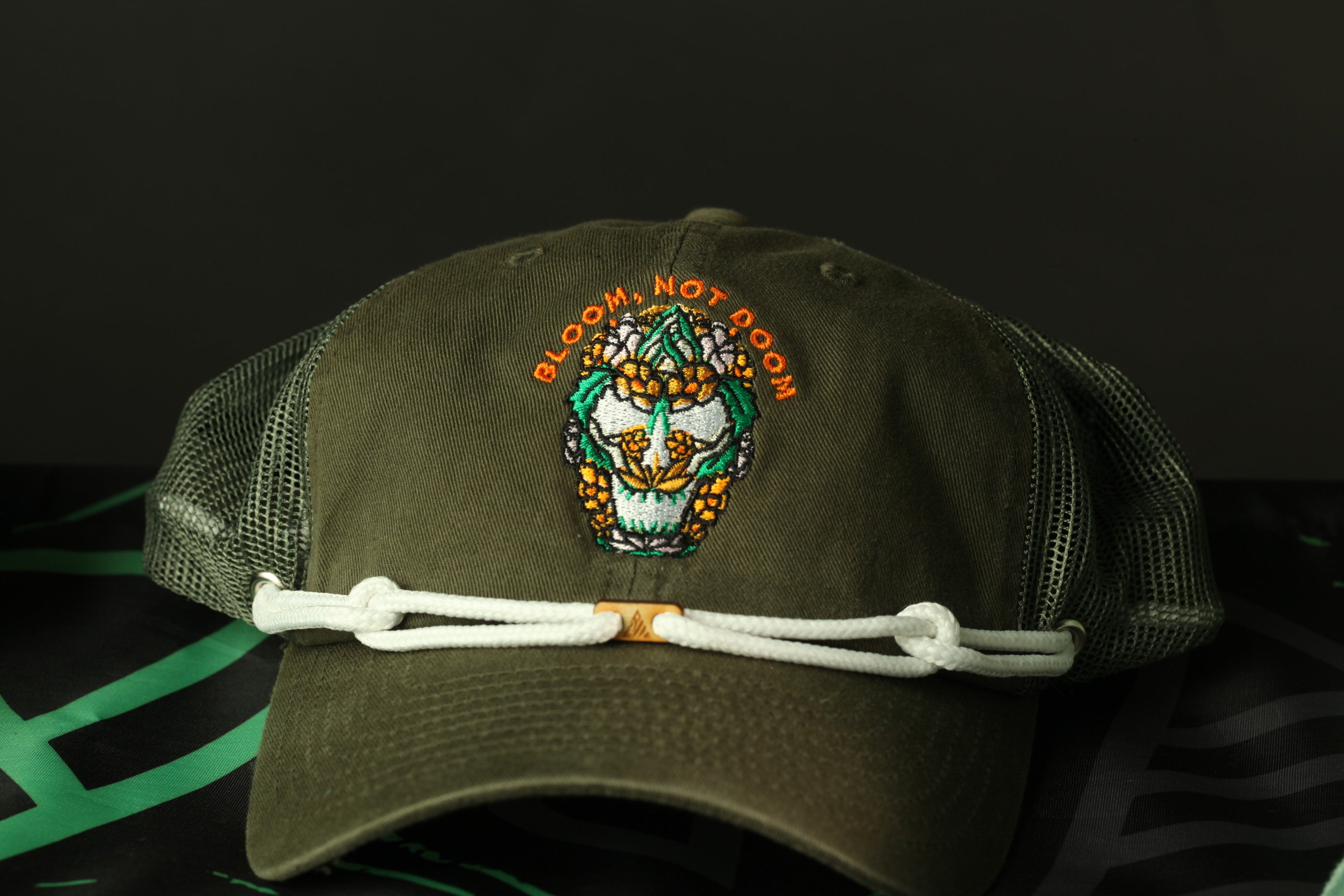 A green baseball cap with a colorful embroidered design on the front, featuring a skull and floral motif.