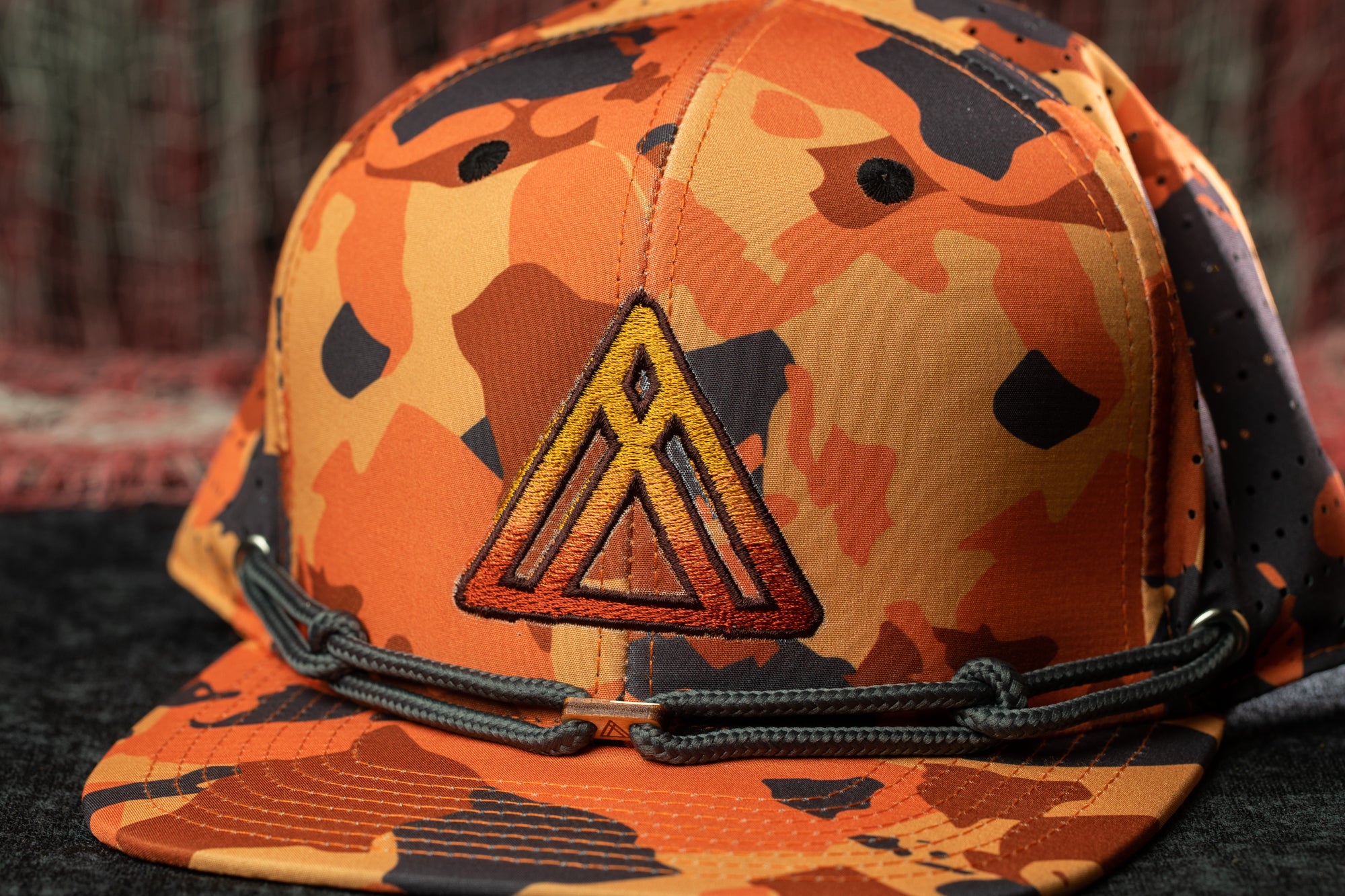 A camouflage baseball cap with a prominent triangle logo on the front.