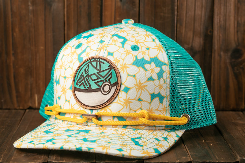 A colorful baseball cap with a floral pattern and a circular patch on the front, sitting on a wooden surface.