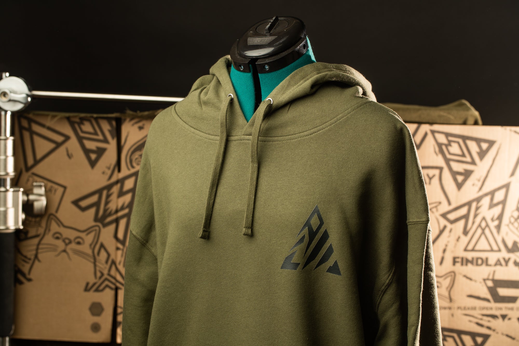 A mannequin wearing a green hoodie with a black triangle design on the front.