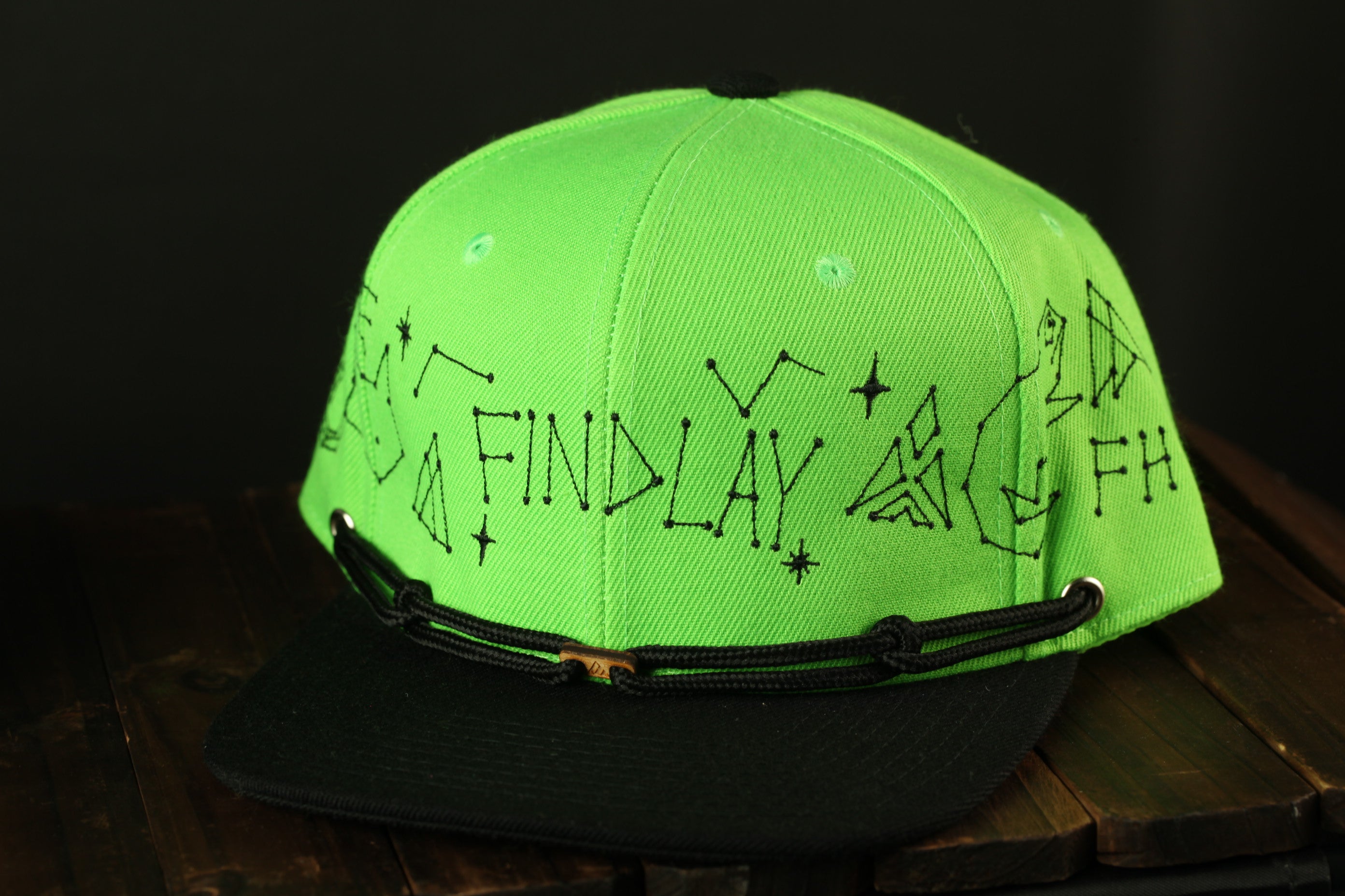 A neon green baseball cap with black text and starry designs on it.