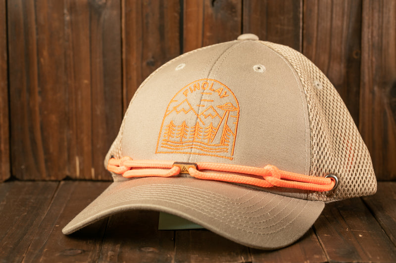 A beige baseball cap with a mesh panel and a printed design on the front, resting on a wooden surface.