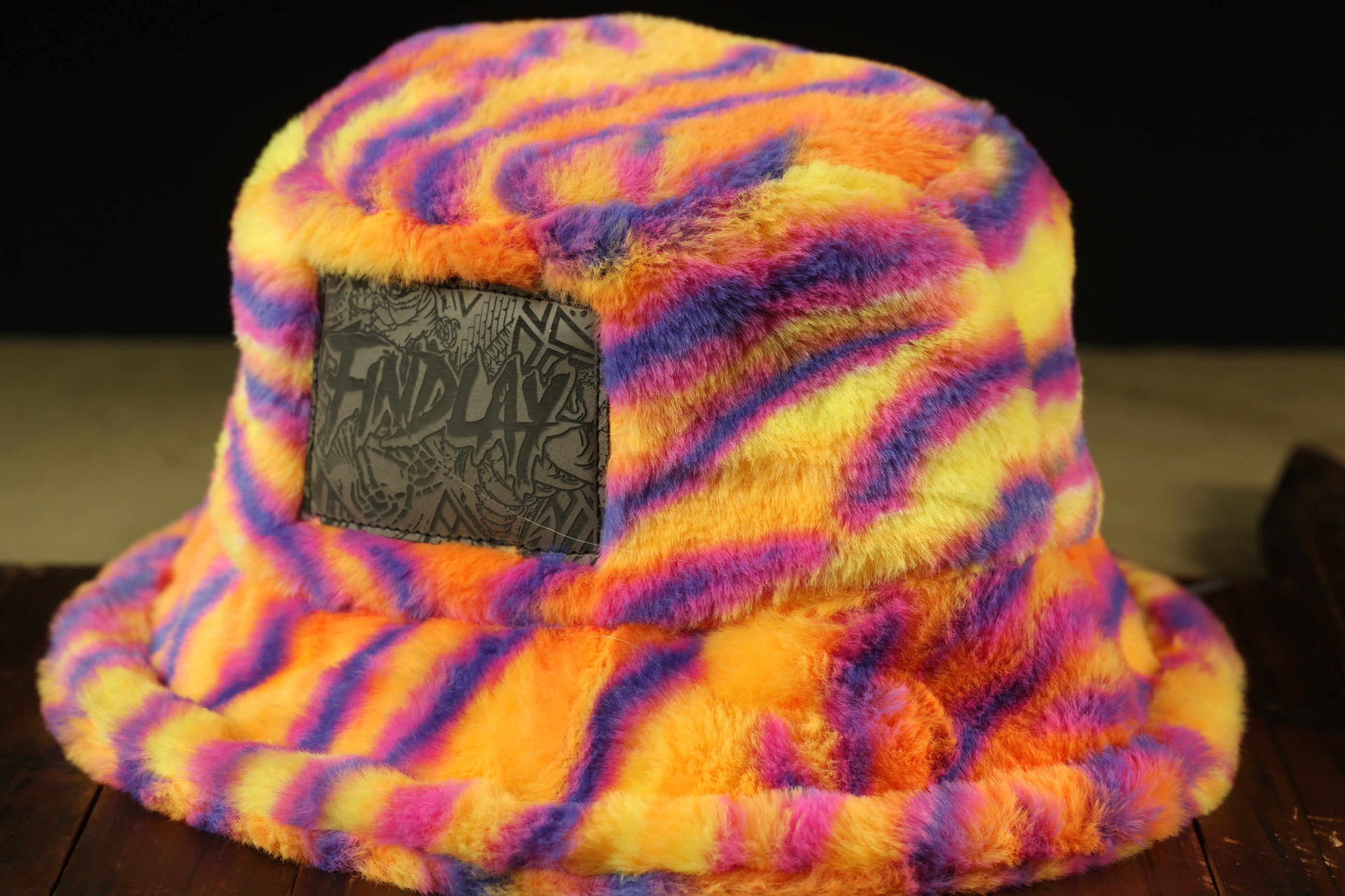 A colorful, fuzzy bucket hat with a black patch on the front.