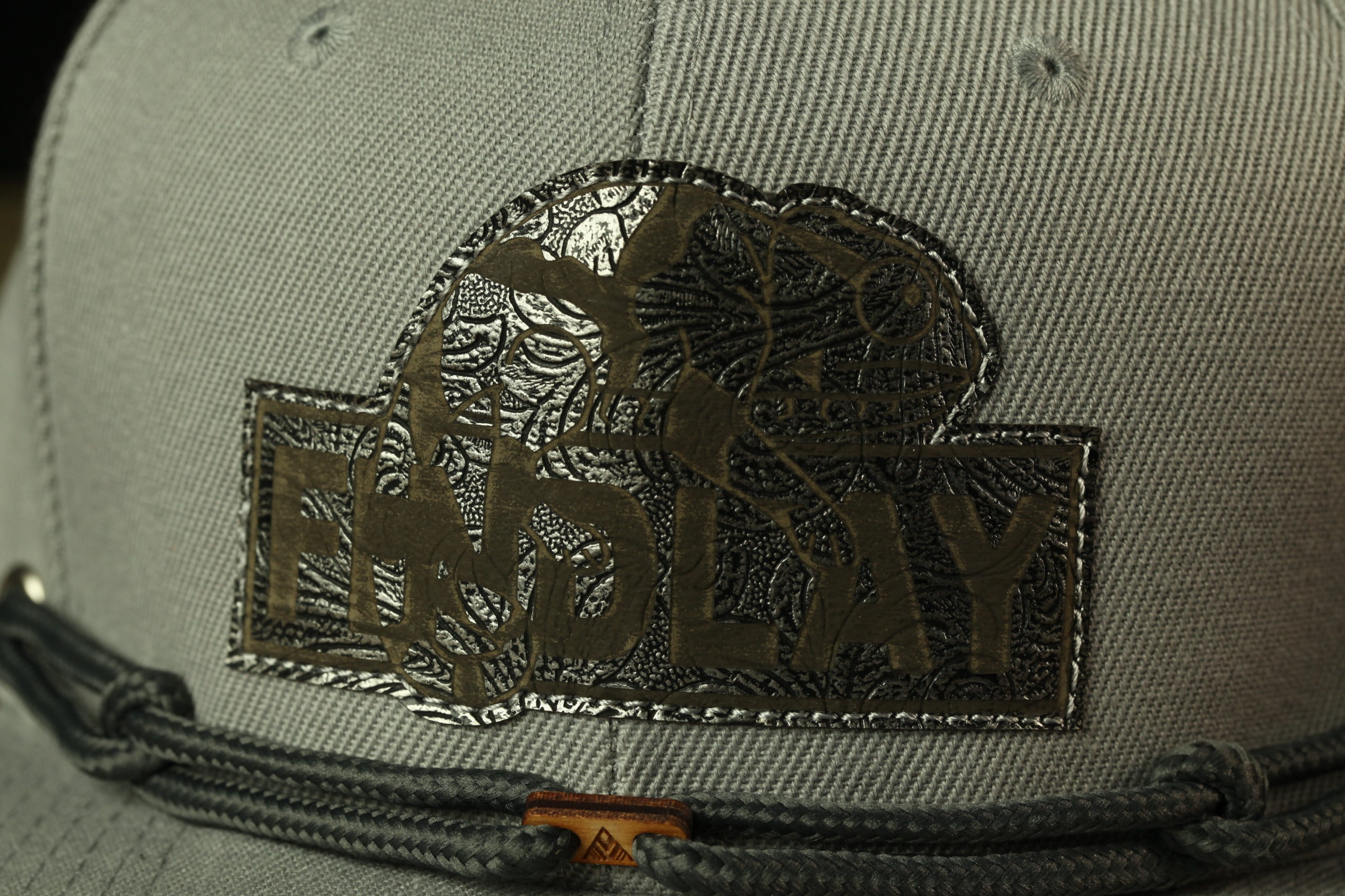 A close-up view of a gray baseball cap with a decorative patch on the front.