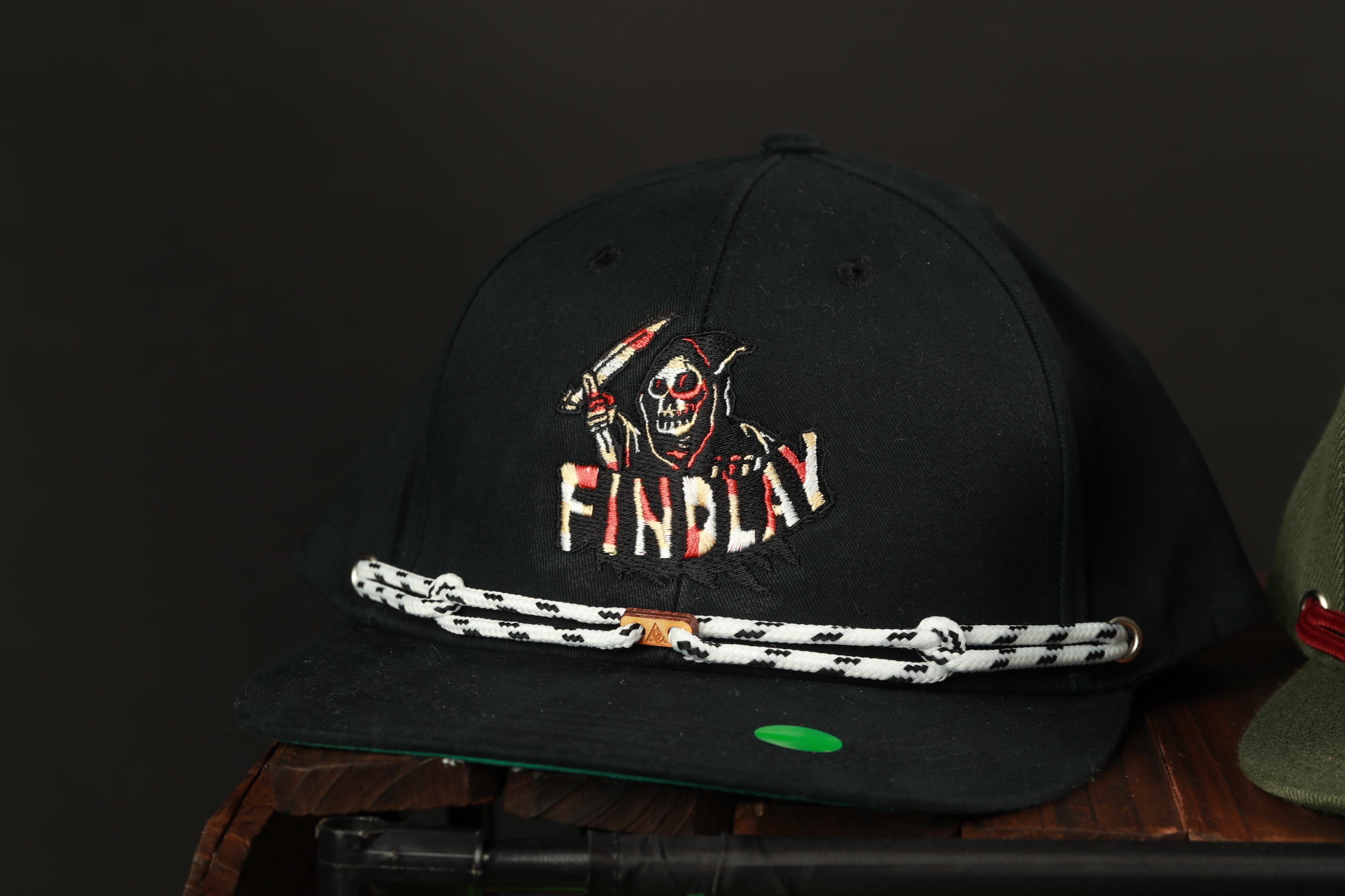 A black baseball cap with a skull and crossbones design and the word "FINDlay" printed on it.