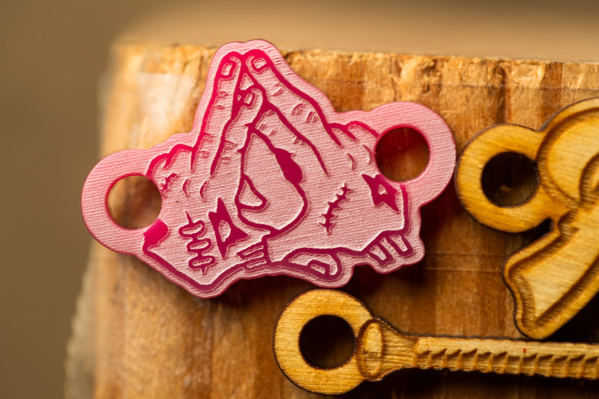 a pink, hand-drawn design on a wooden surface, with a wooden key-like shape in the foreground.