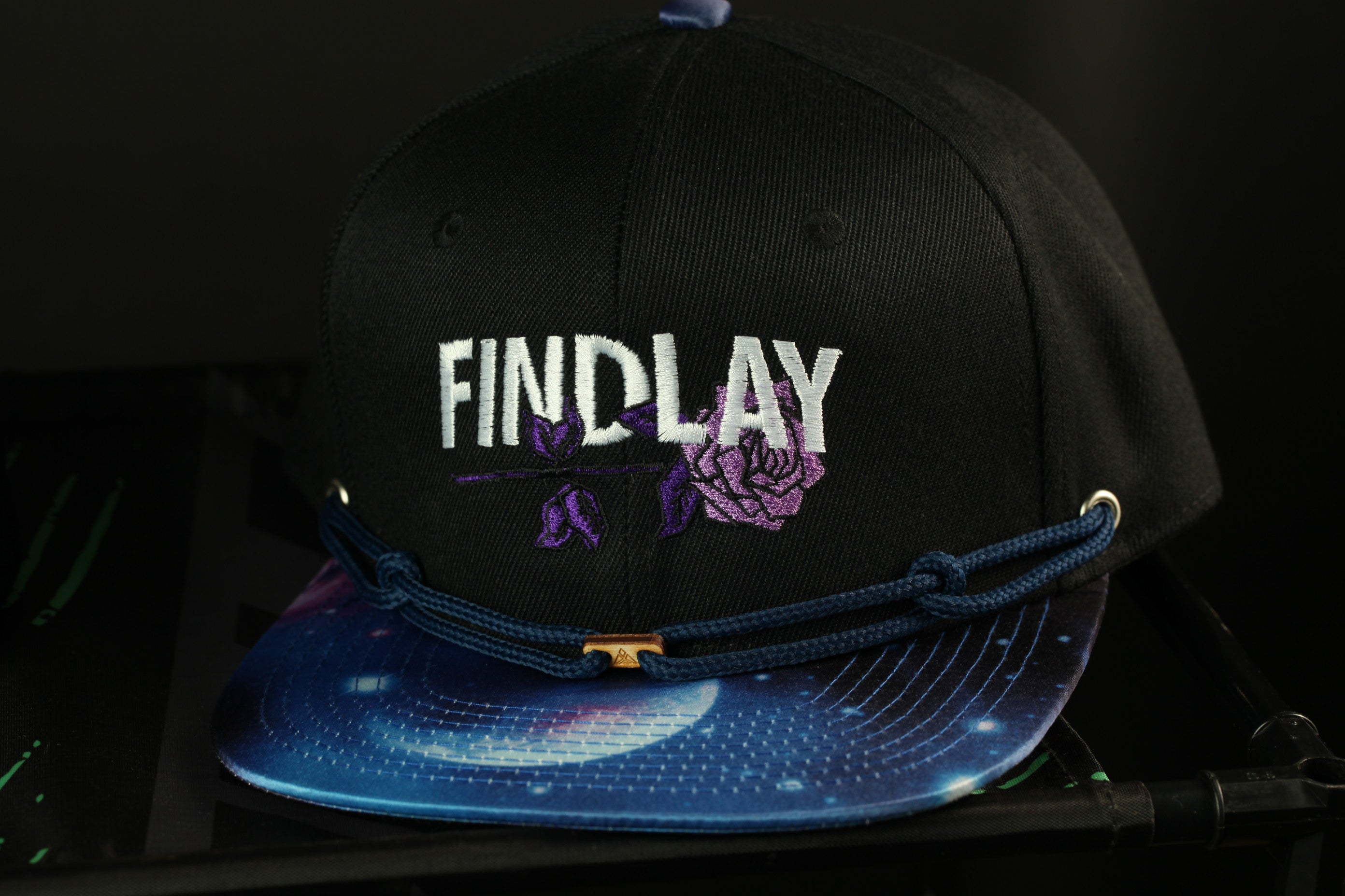 A black baseball cap with the word "FINDlay" embroidered on it, along with a space-themed design on the brim.