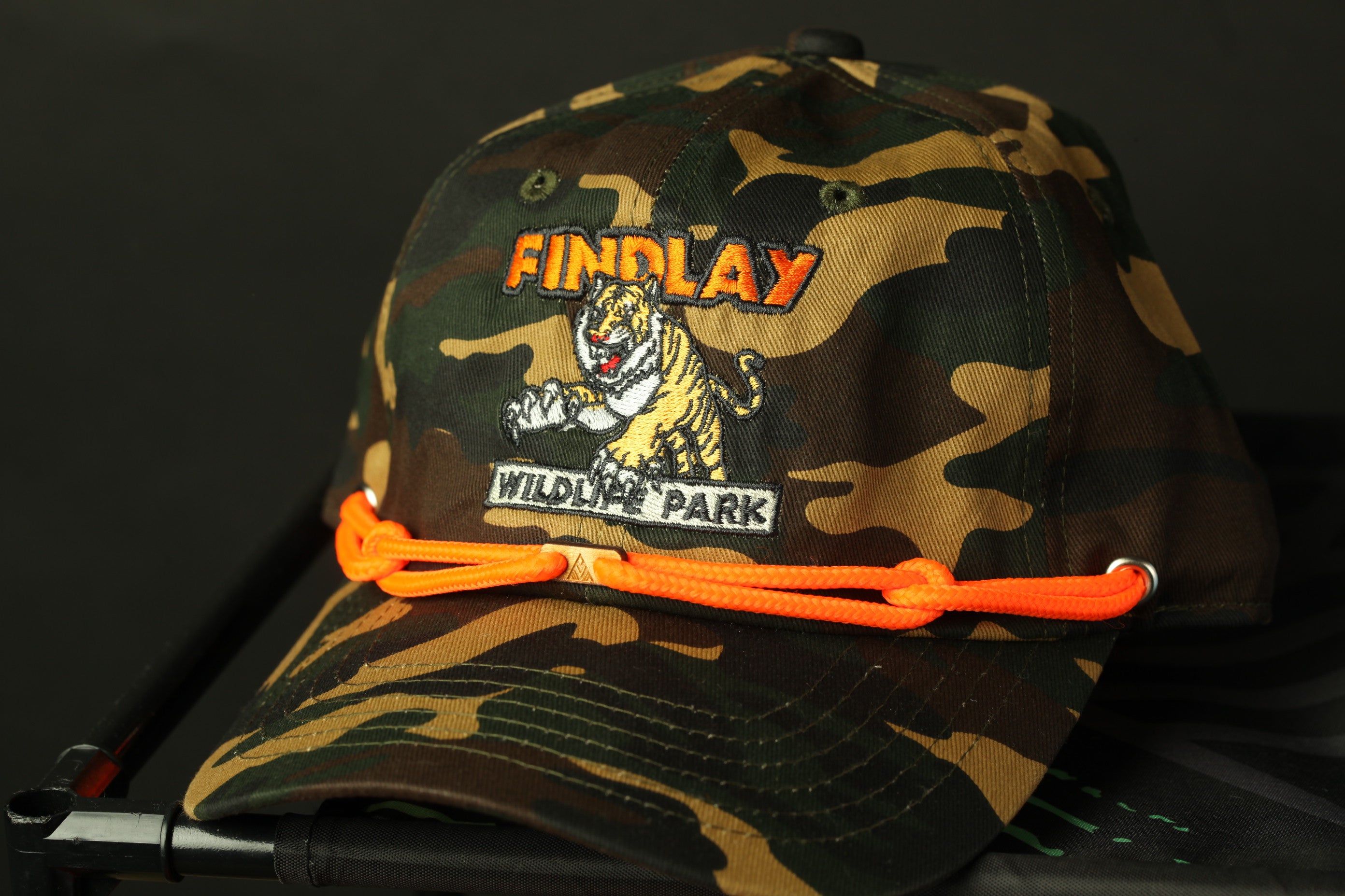 A camouflage baseball cap with a tiger logo and the text "FINDLAY WILDLIFE PARK" printed on it.