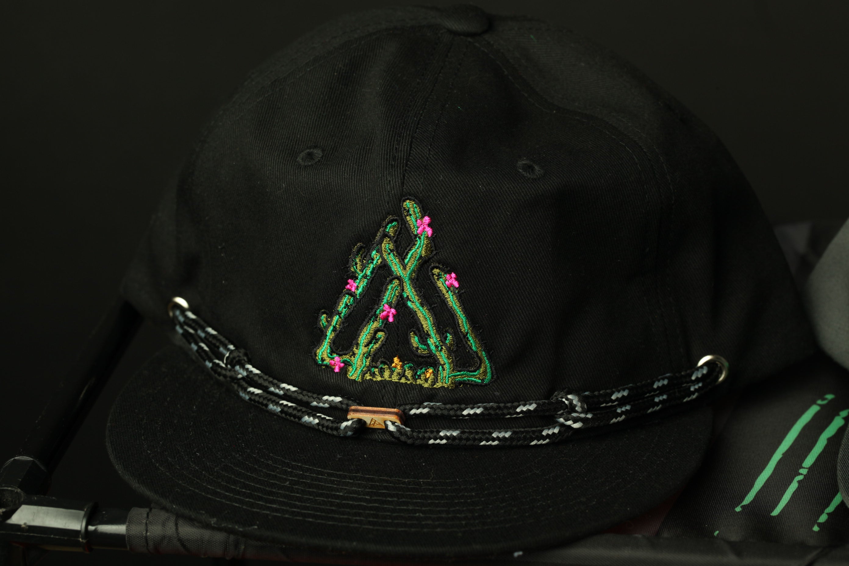 A black baseball cap with a green and pink floral embroidered design on the front.