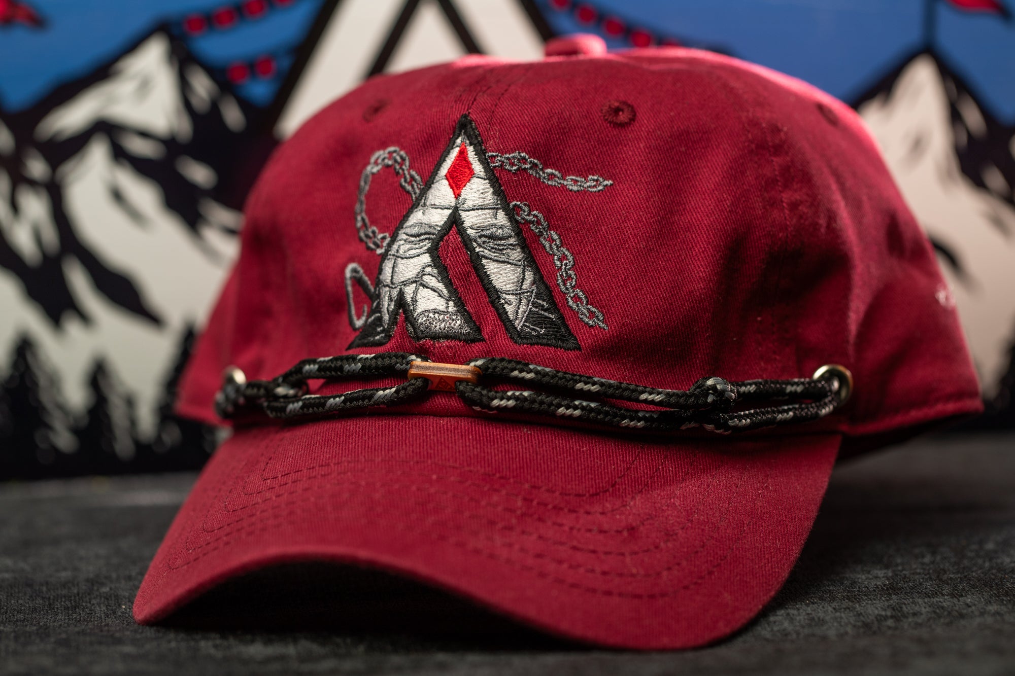 A red baseball cap with a black and white logo on the front, sitting on a gray surface.