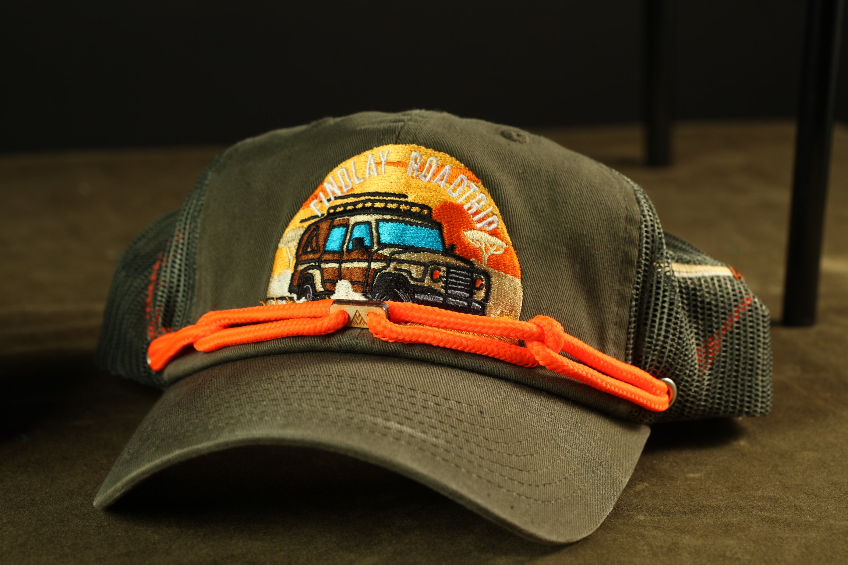 A green baseball cap with an embroidered design of a car and the text "FINDLAY COLORADO" printed on it.