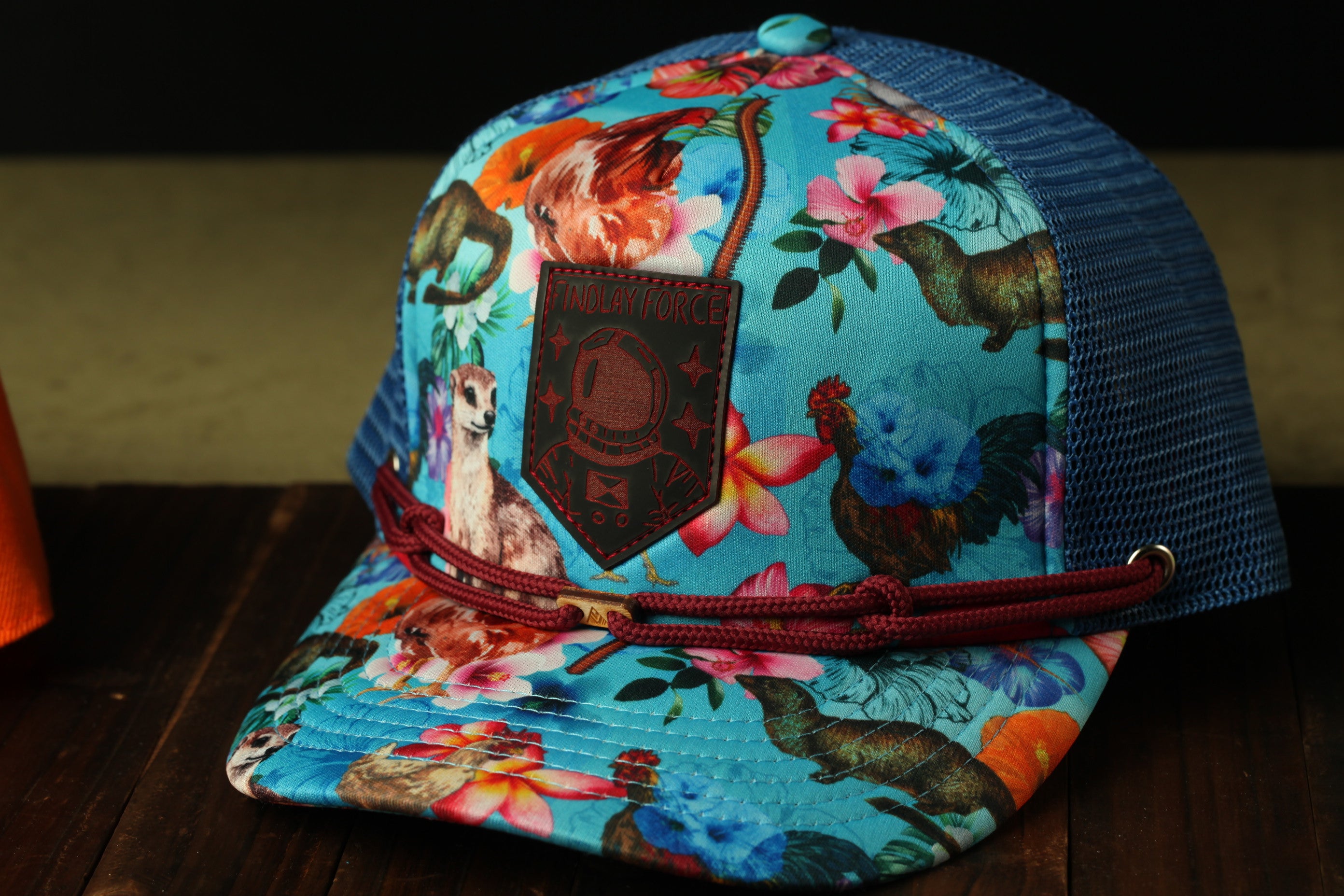 A colorful floral-patterned baseball cap with a red string and a small patch on the front.