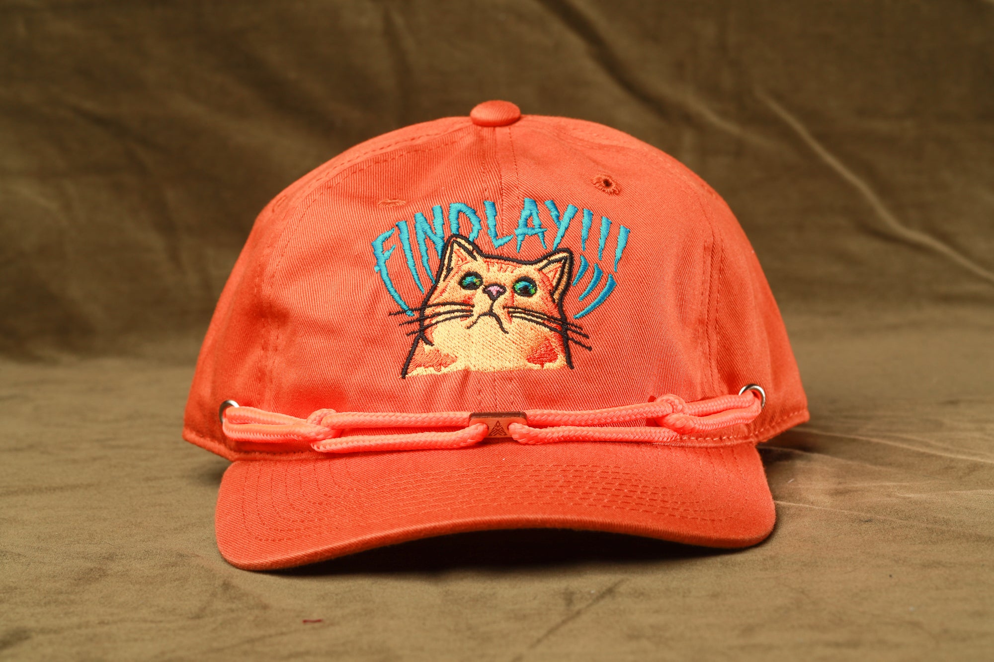 An orange baseball cap with a cat embroidered on it, featuring the text "FIND LAY!!!"