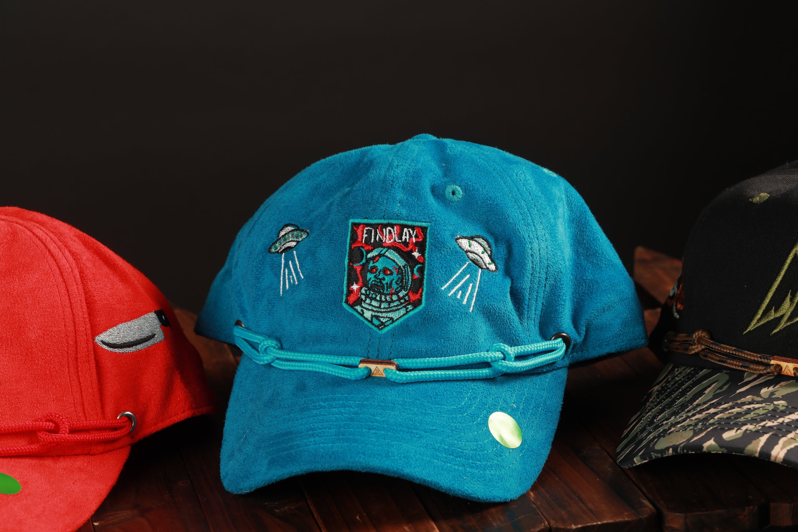 A collection of colorful baseball caps is displayed on a wooden surface, with one prominently featuring a blue cap with a unique design.
