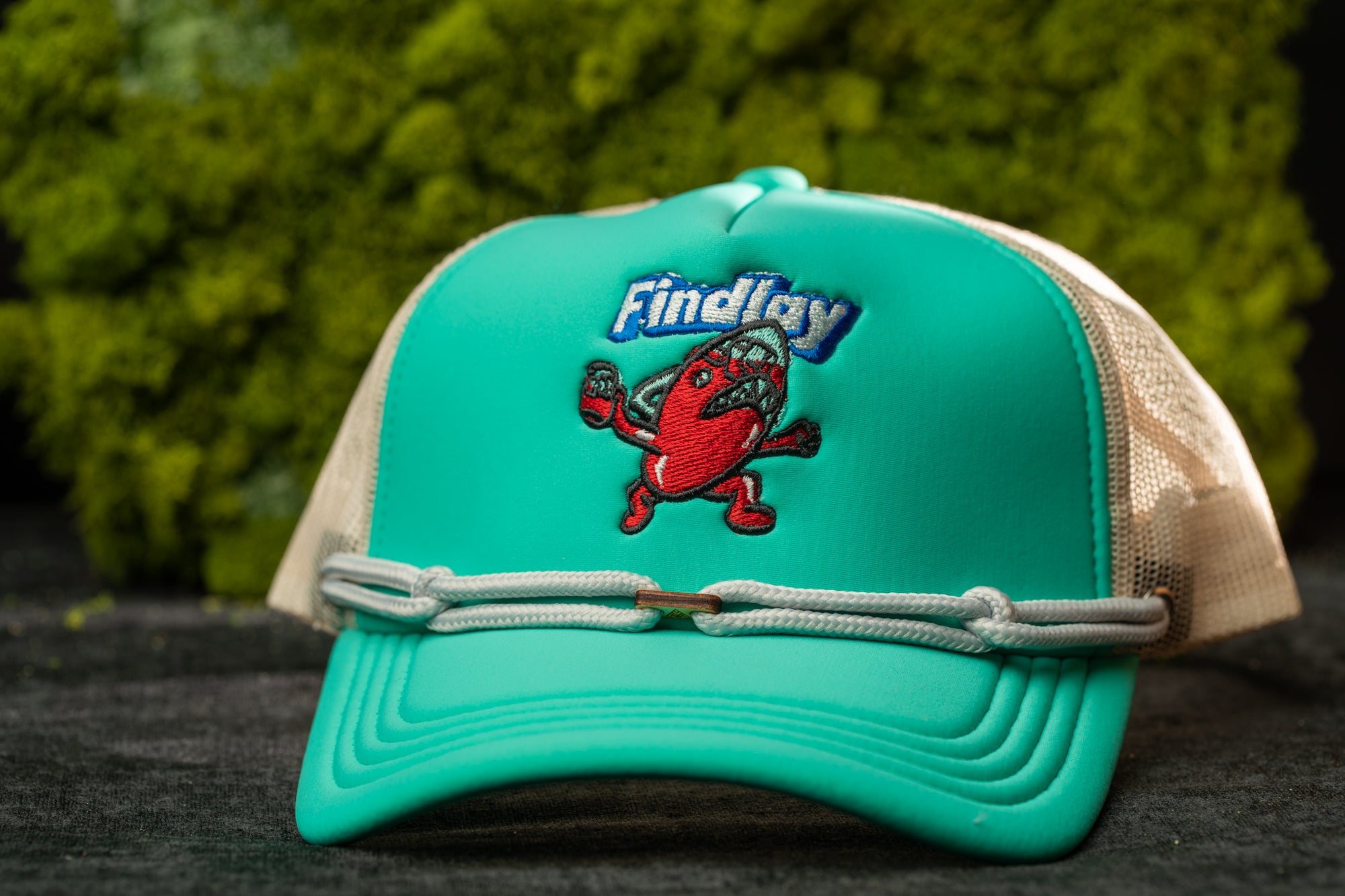 A turquoise baseball cap with a cartoon character on it, featuring the text "Findlay" on the front.
