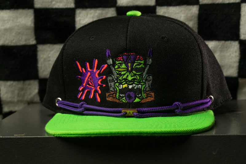 A black baseball cap with a colorful graphic design on the front, including a green and purple character, is displayed against a black and white checkered background.