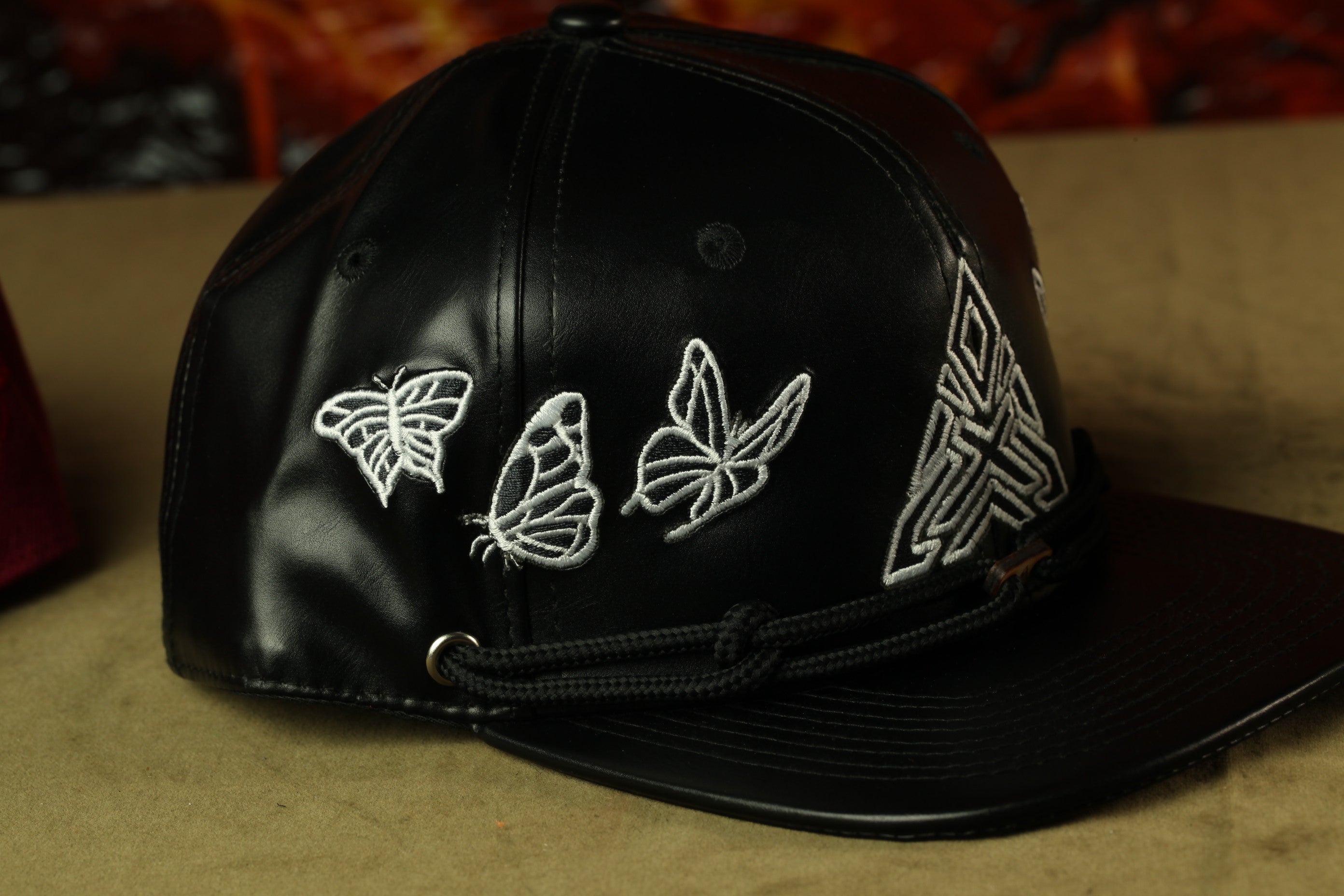 A black baseball cap with white embroidered butterflies on the front.