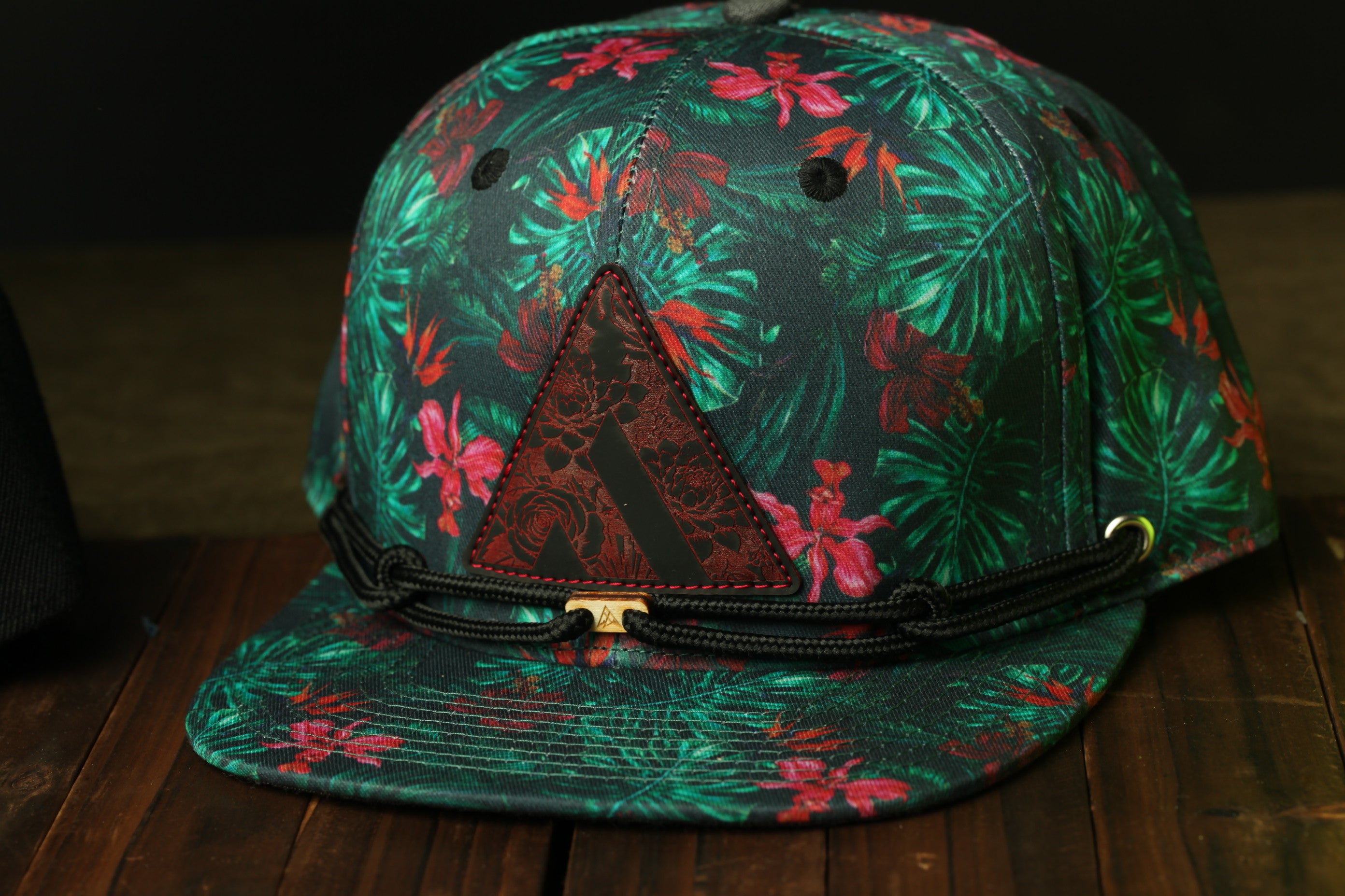 A colorful floral print baseball cap with a triangular patch on the front.
