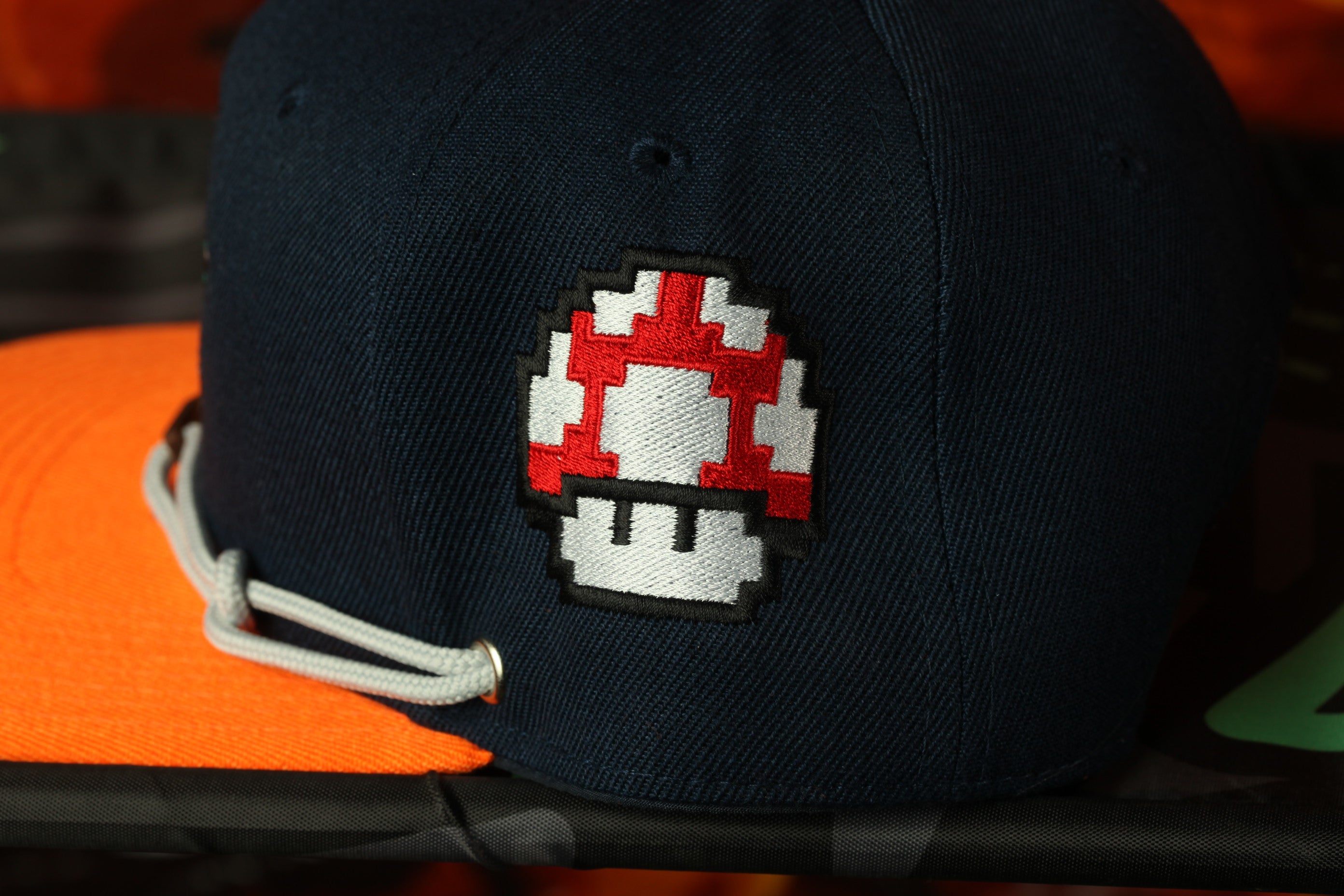 A close-up view of a black baseball cap with a red and white mushroom patch on the front.