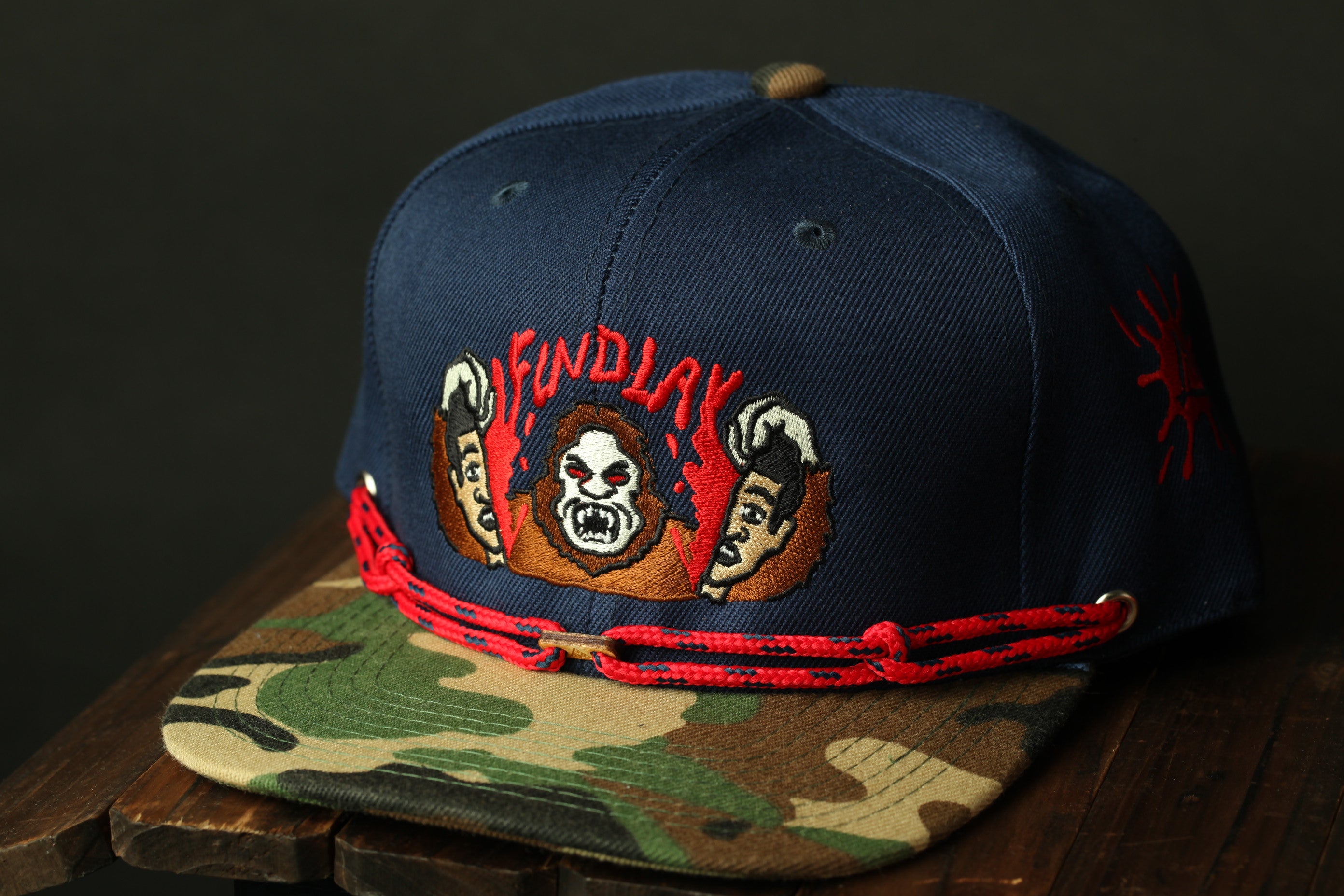 A navy blue baseball cap with a camouflage pattern and a red string around the brim.