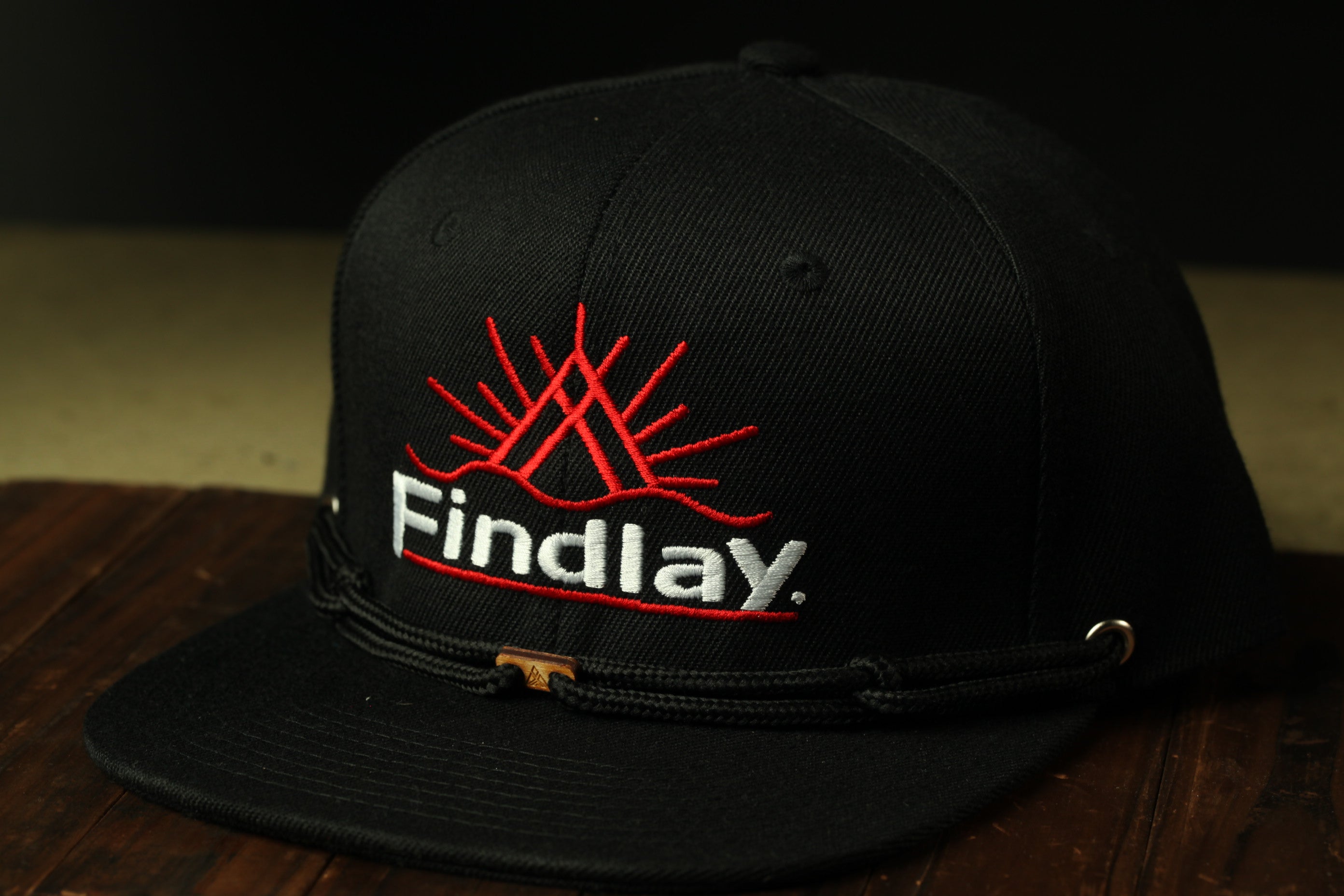 A black baseball cap with a red logo and the word "Findlay" printed on it.