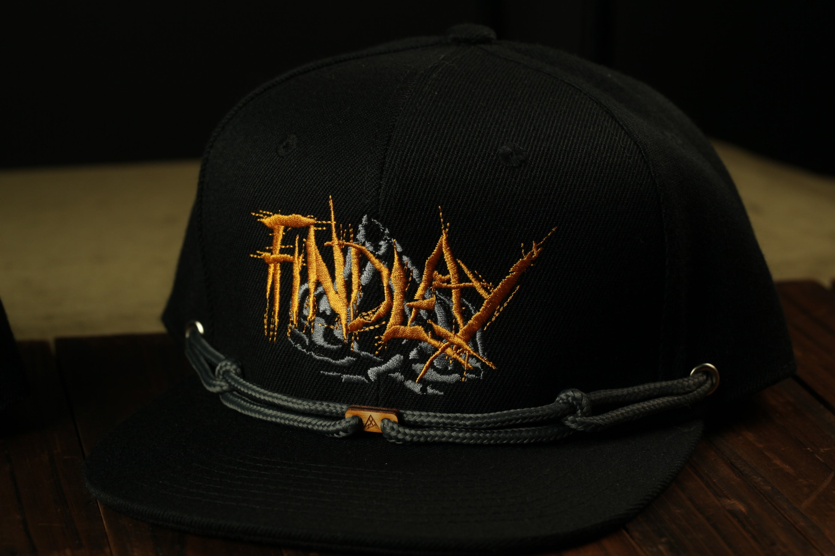 A black baseball cap with a gold embroidered logo on the front.