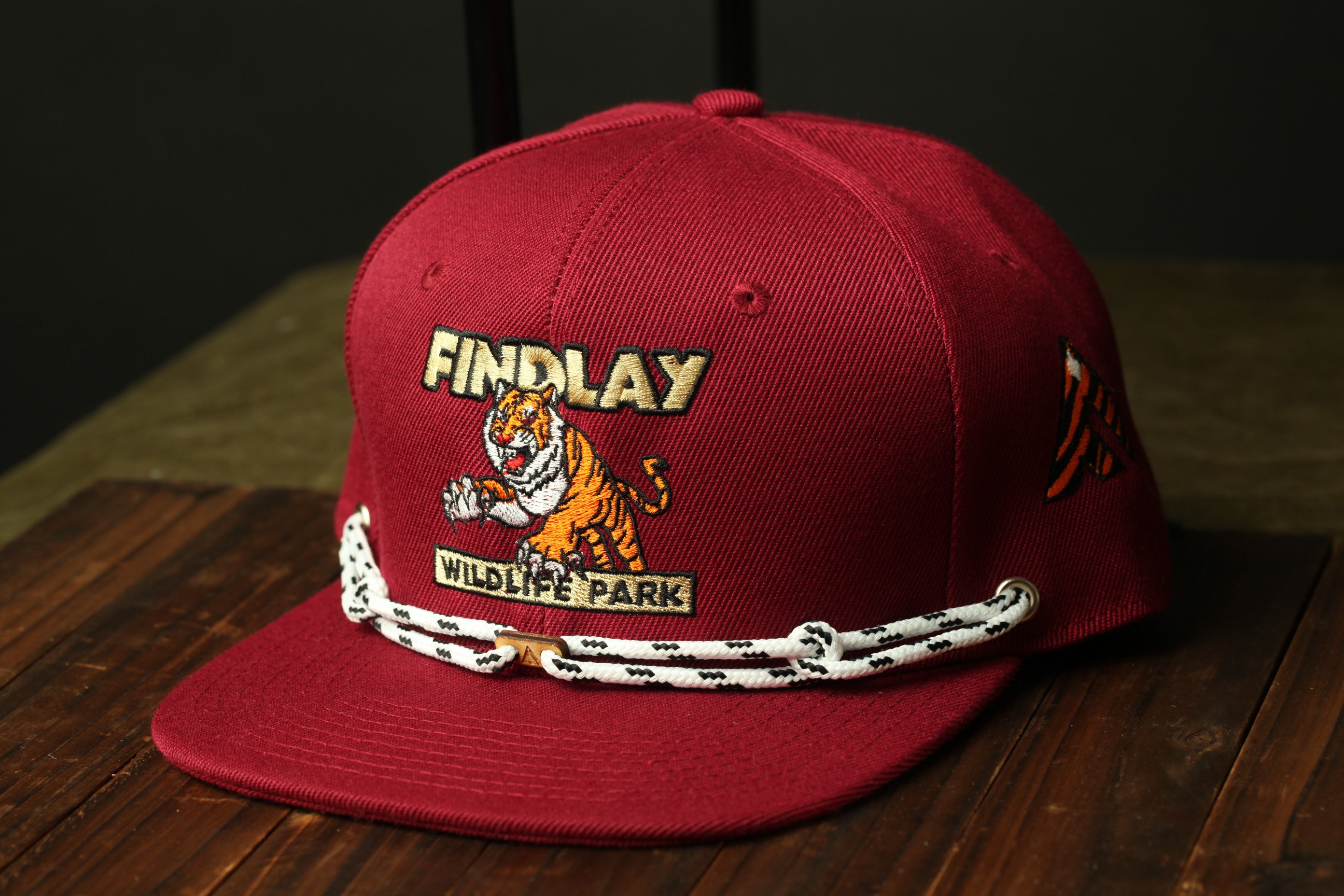 A red baseball cap with a tiger graphic and the text "FINDLAY WILDLIFE PARK" printed on it.