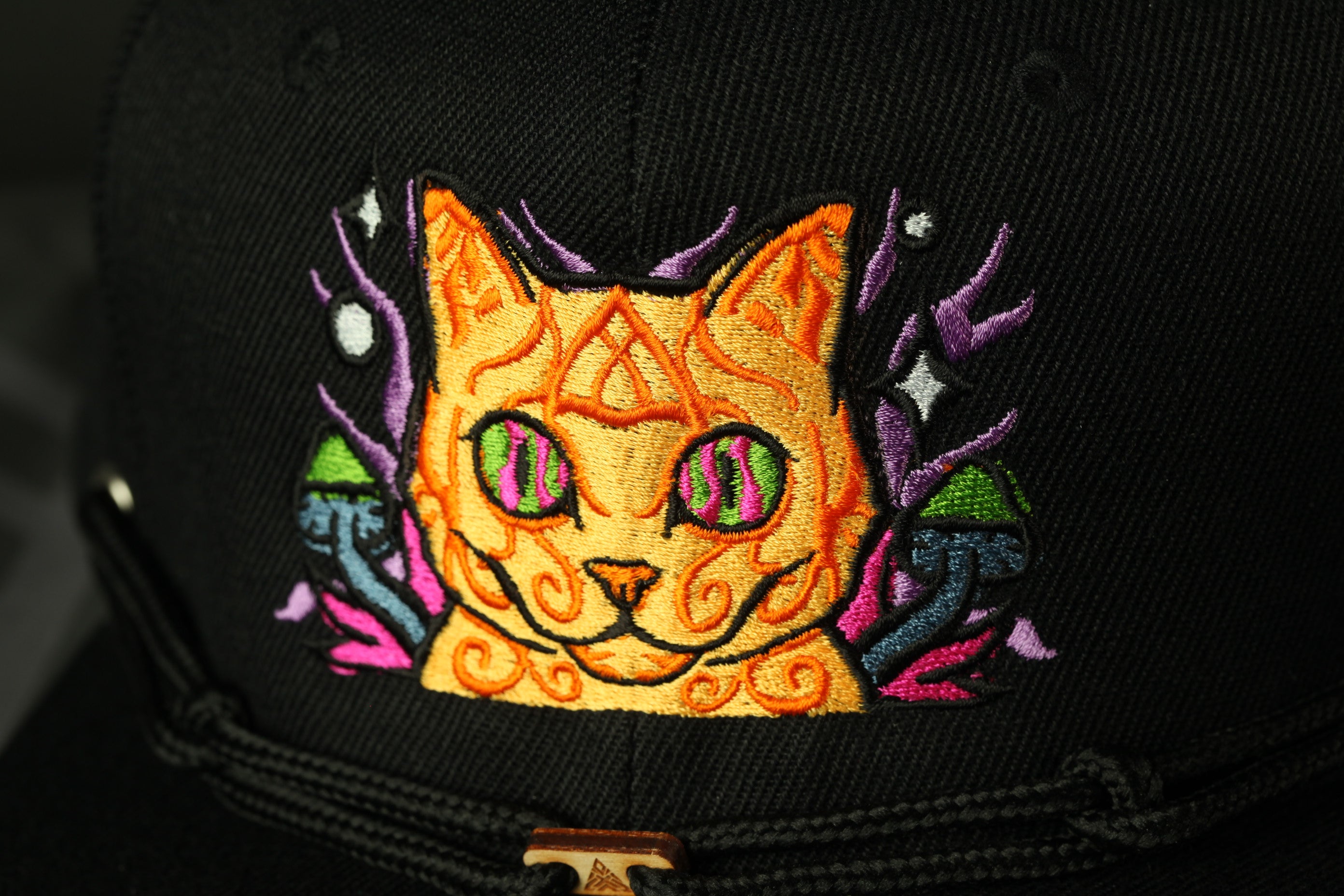 a close-up view of a black baseball cap with a colorful, embroidered design on the front.