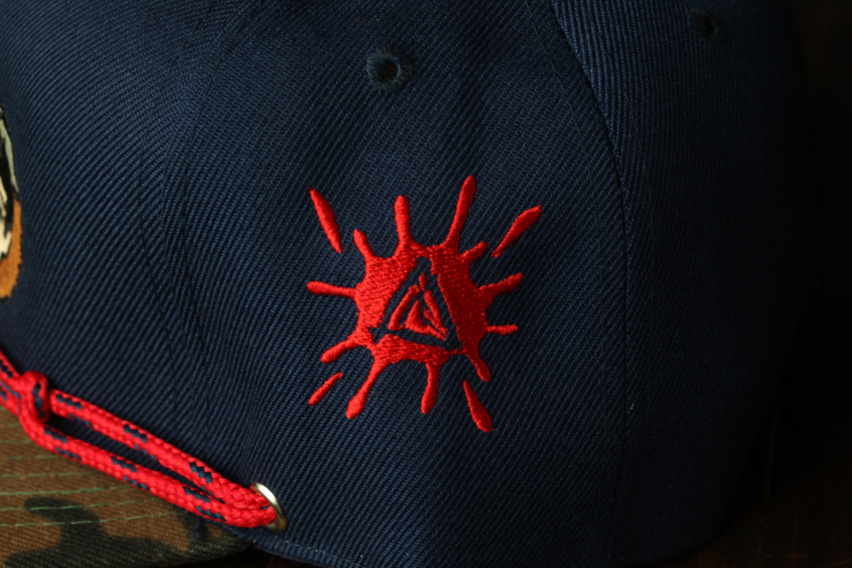 a close-up view of a dark blue baseball cap with a red embroidered design on the front.