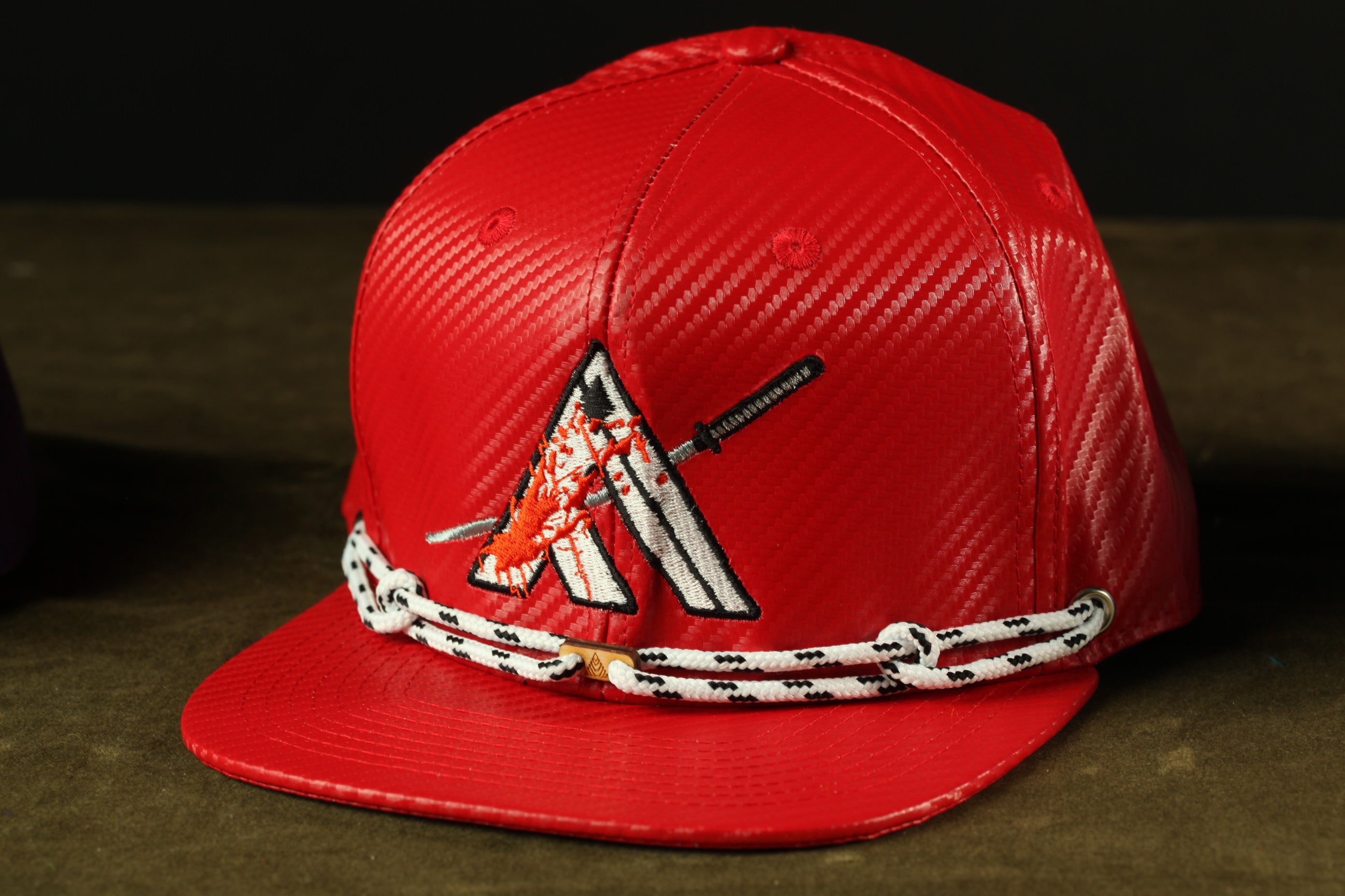 A red baseball cap with a white and black graphic design on the front.