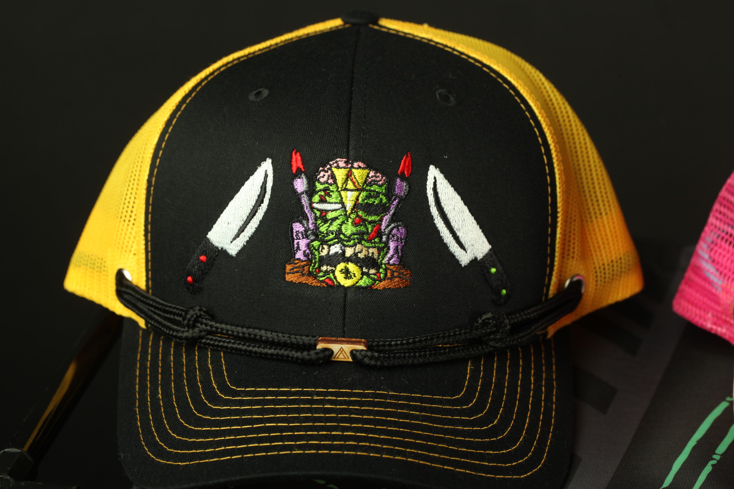 A black and yellow baseball cap with a colorful, embroidered design on the front.