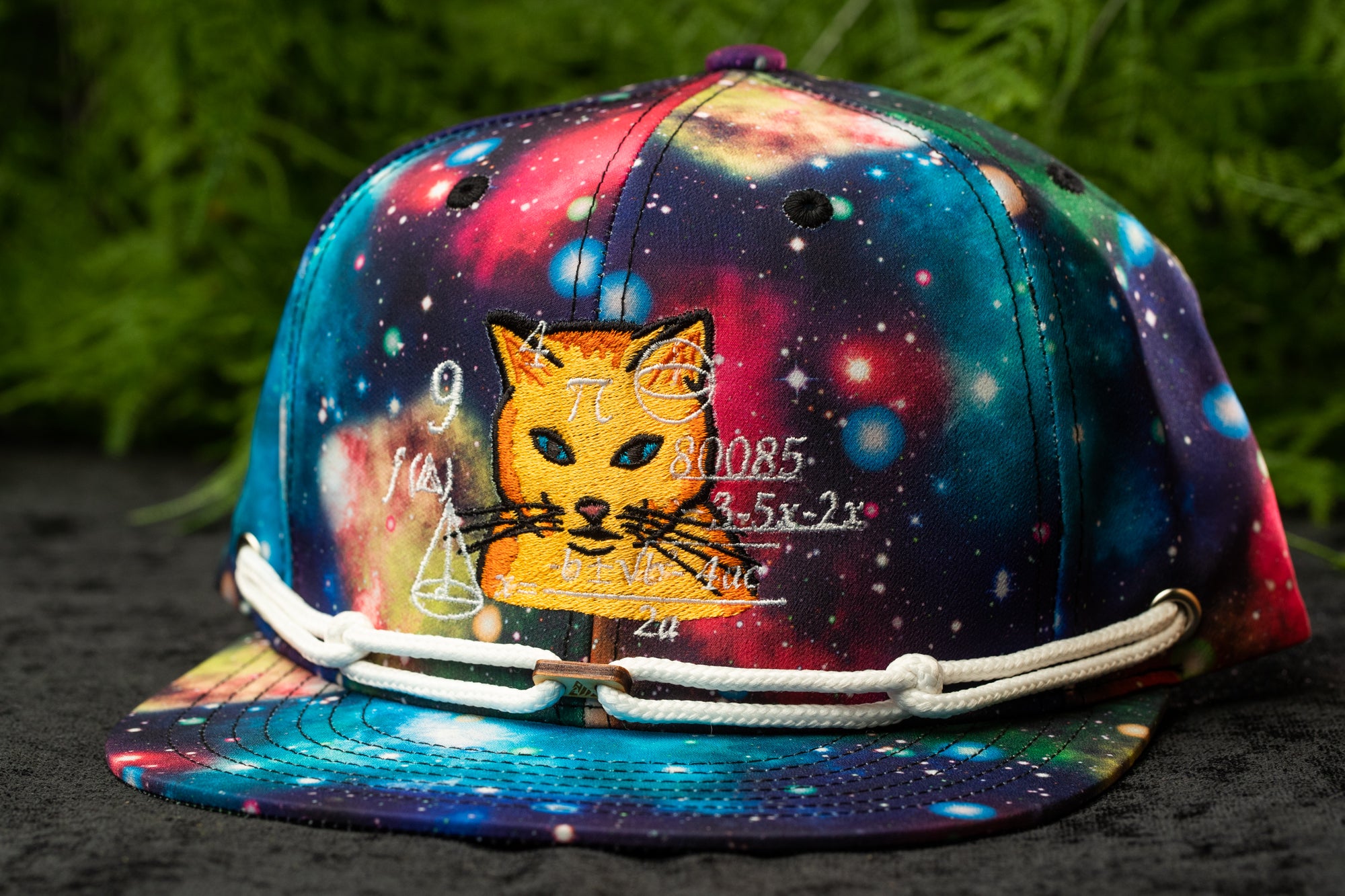 A colorful, galaxy-themed baseball cap with a cat design and various mathematical equations printed on it.