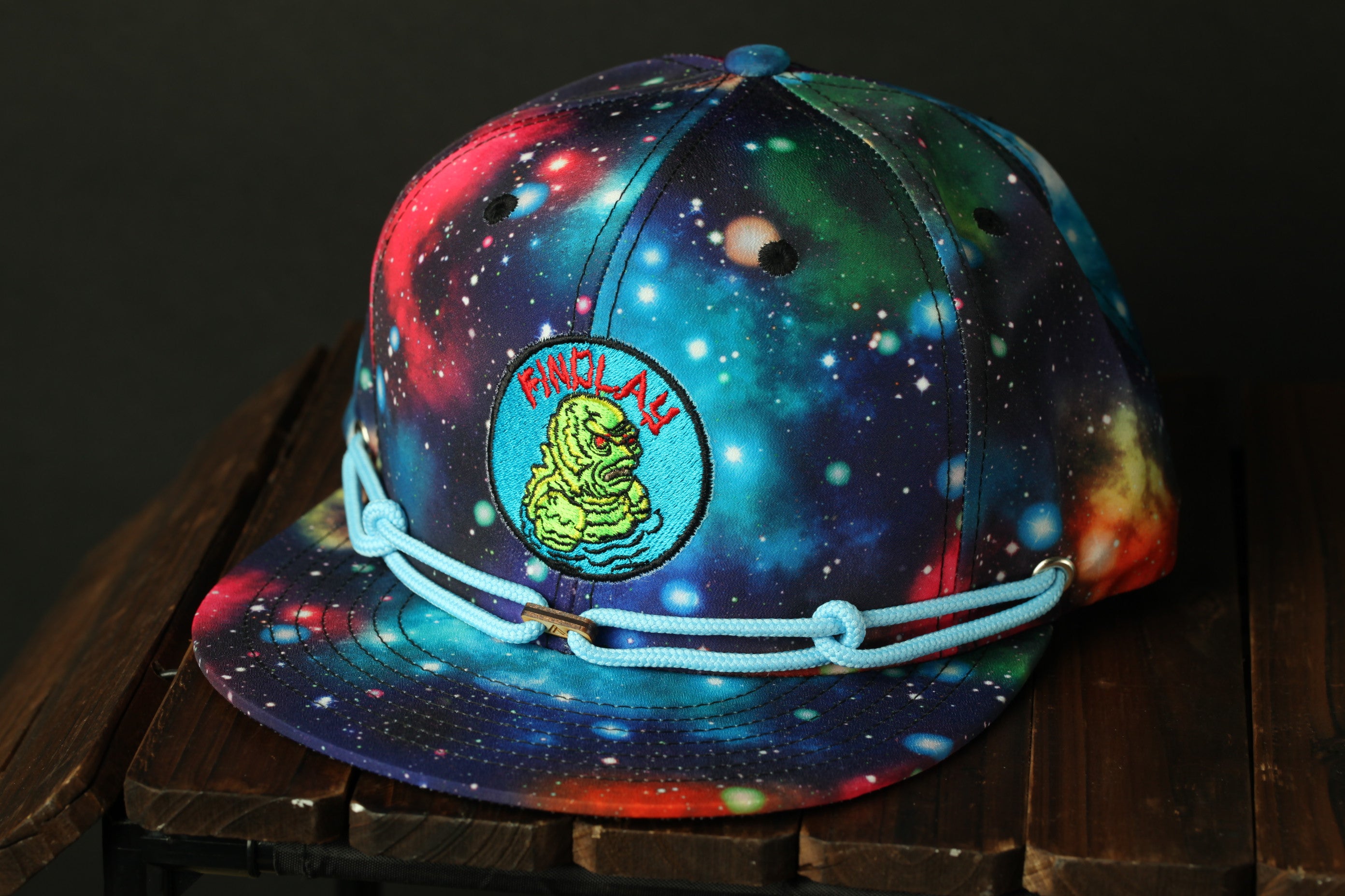 A colorful, space-themed baseball cap with a galaxy pattern and a small embroidered logo on the front.