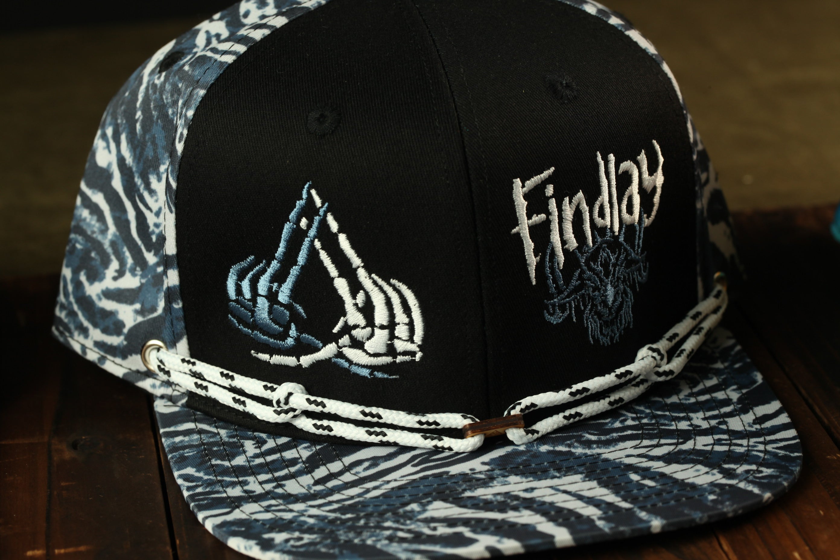 A black baseball cap with a zebra print pattern and a white string around the brim.