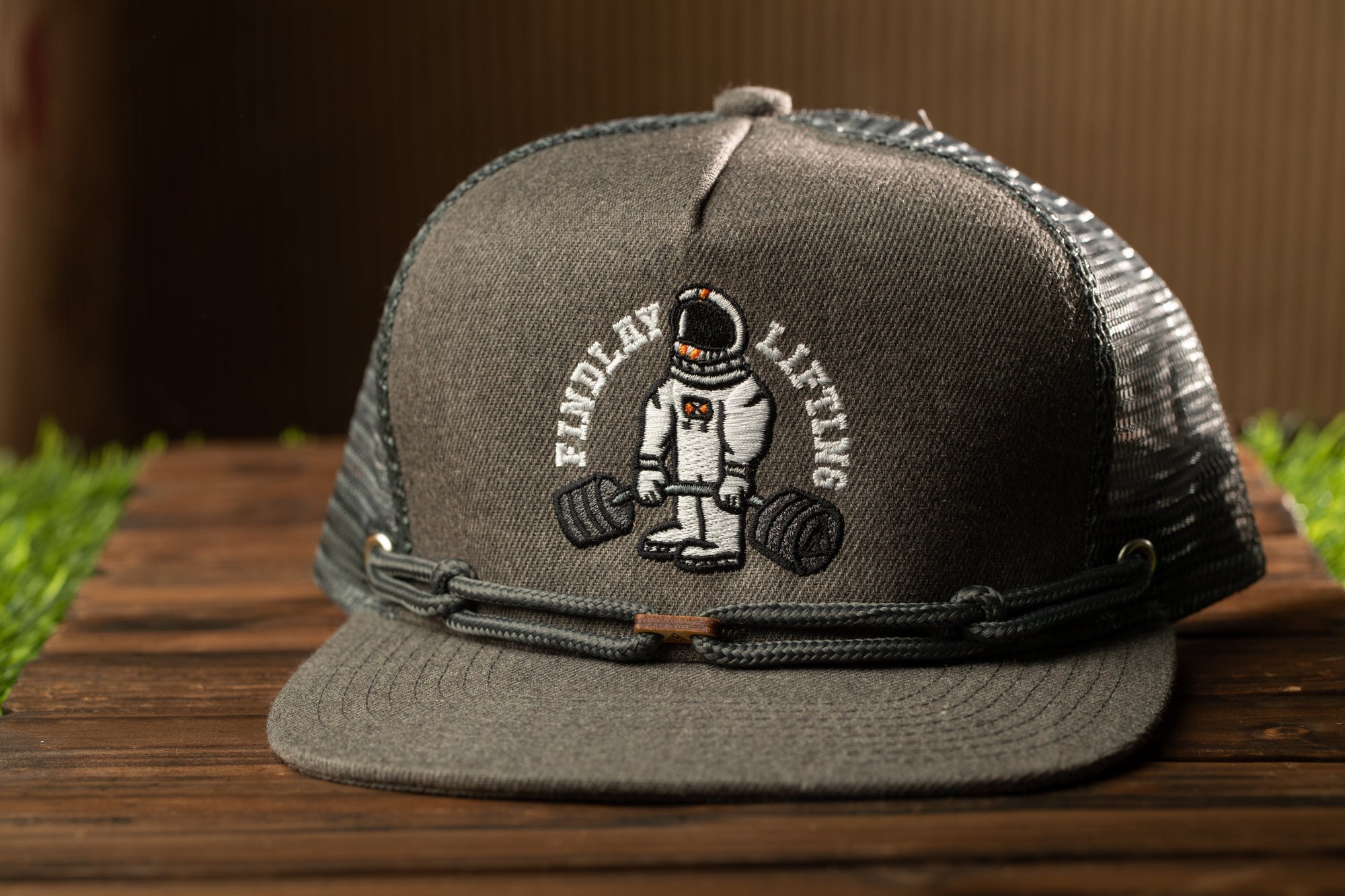 A gray baseball cap with a graphic of an astronaut lifting weights, along with the text "FINDlayLifting" printed on it.