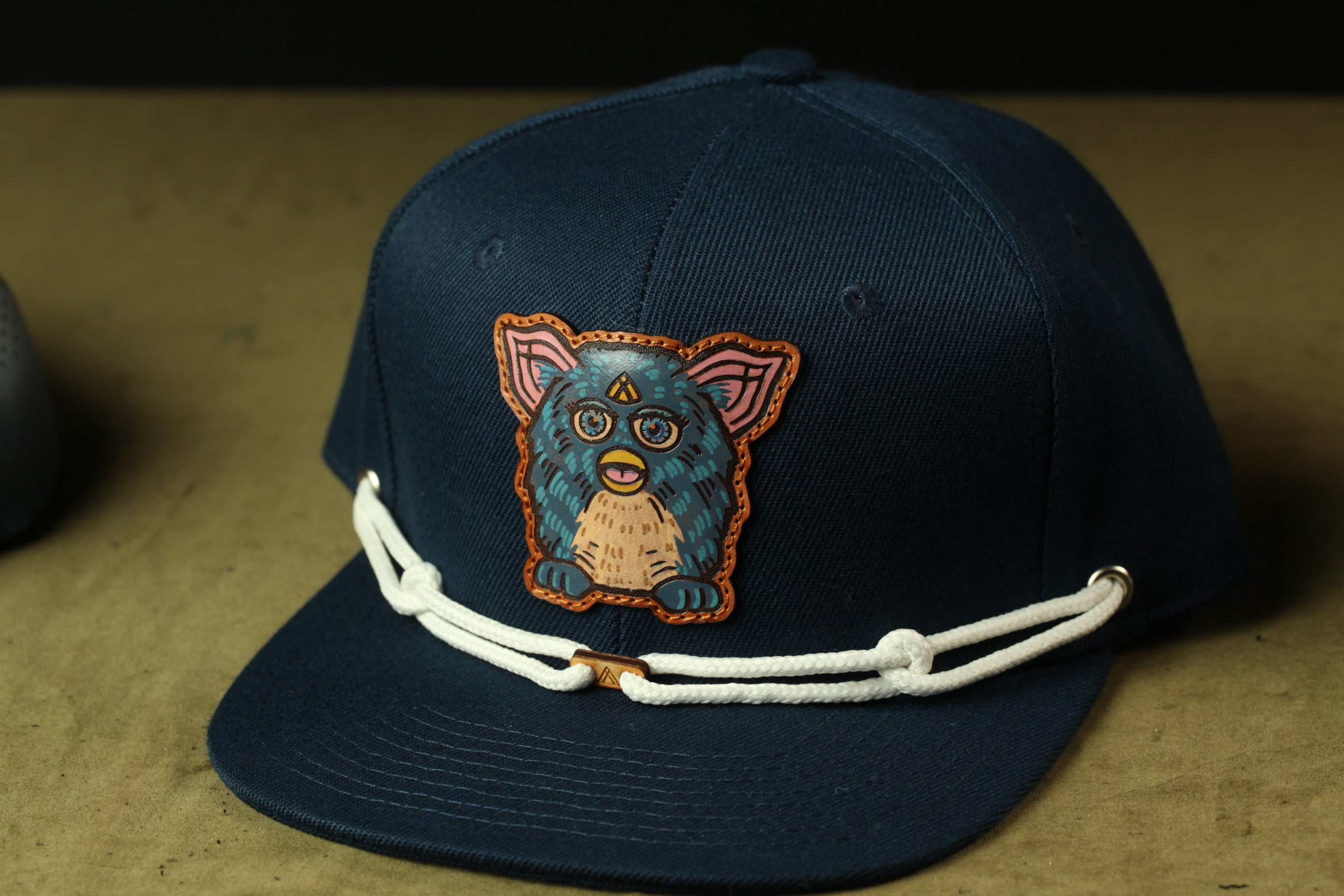 A navy blue baseball cap with a colorful cartoon character design on the front.