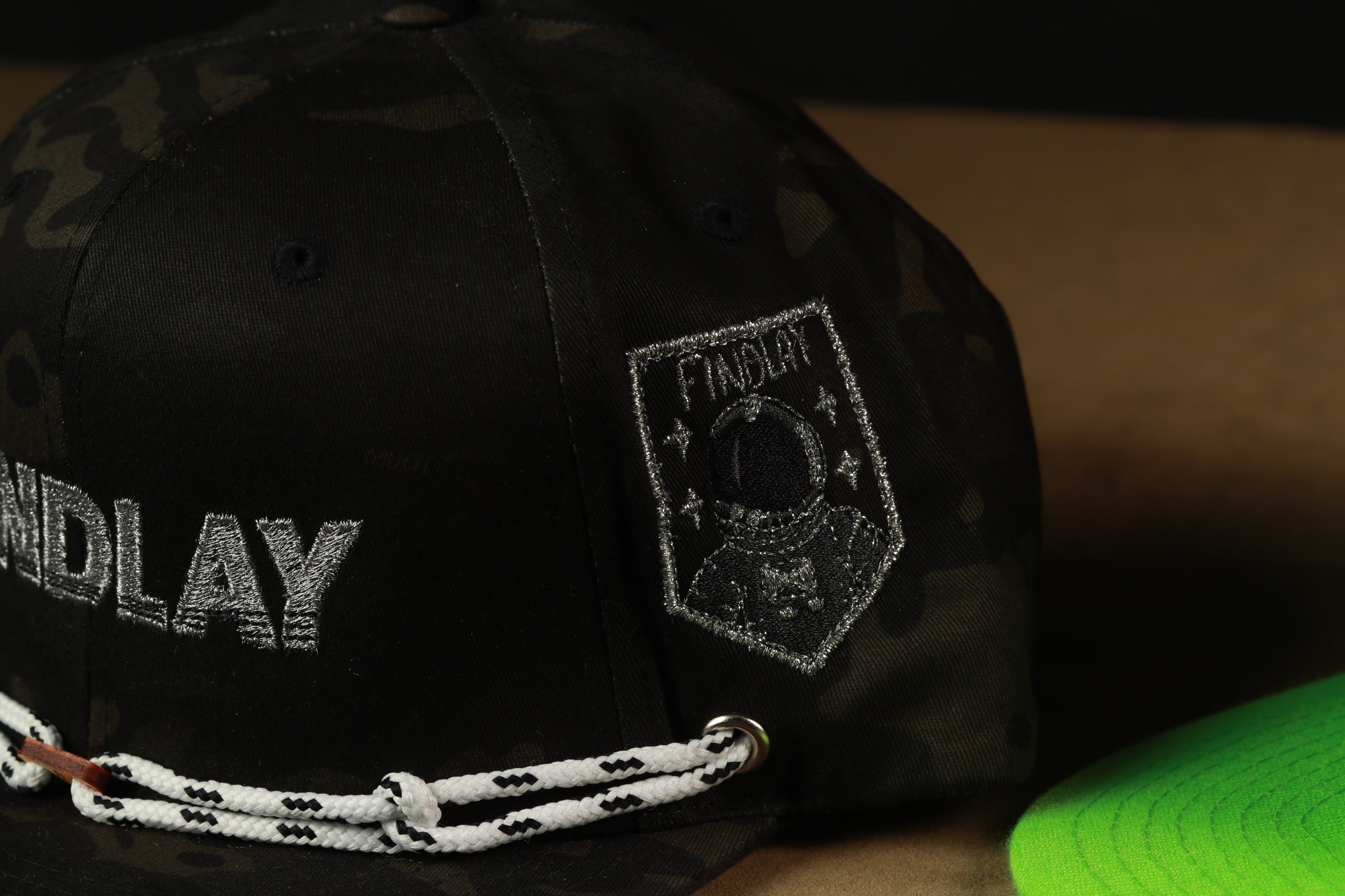 A black camouflage baseball cap with a patch featuring an astronaut and the word "PADDLER" on the side.