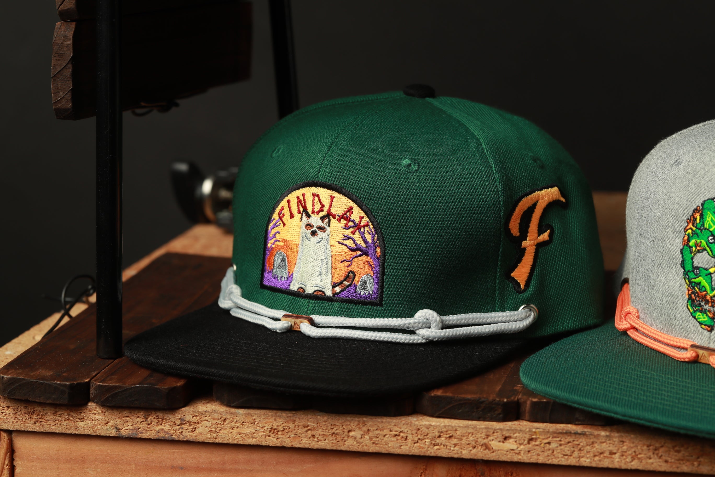 two baseball caps, one green and one gray, placed on a wooden surface.