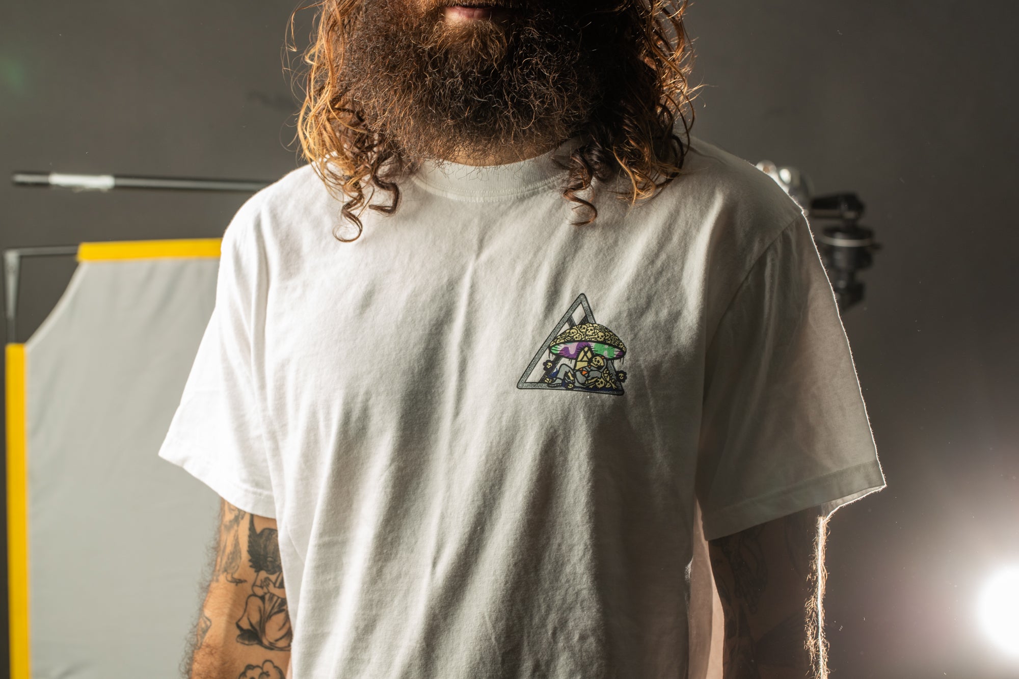 A person with a long beard wearing a white t-shirt with a graphic design on it.