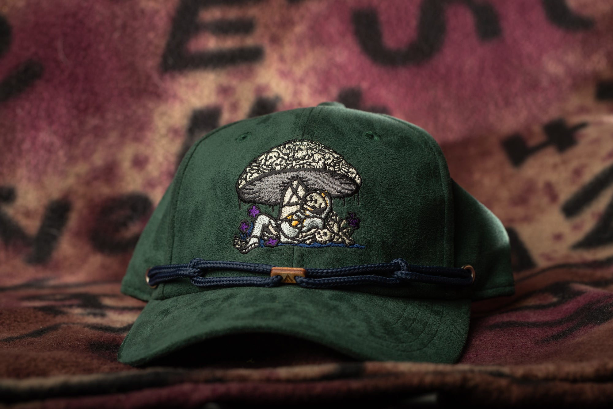 A green baseball cap with an embroidered design on the front, featuring a mushroom and a person.