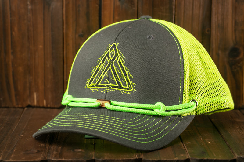 A gray baseball cap with a yellow mesh panel and a green rope strap, placed on a wooden surface.