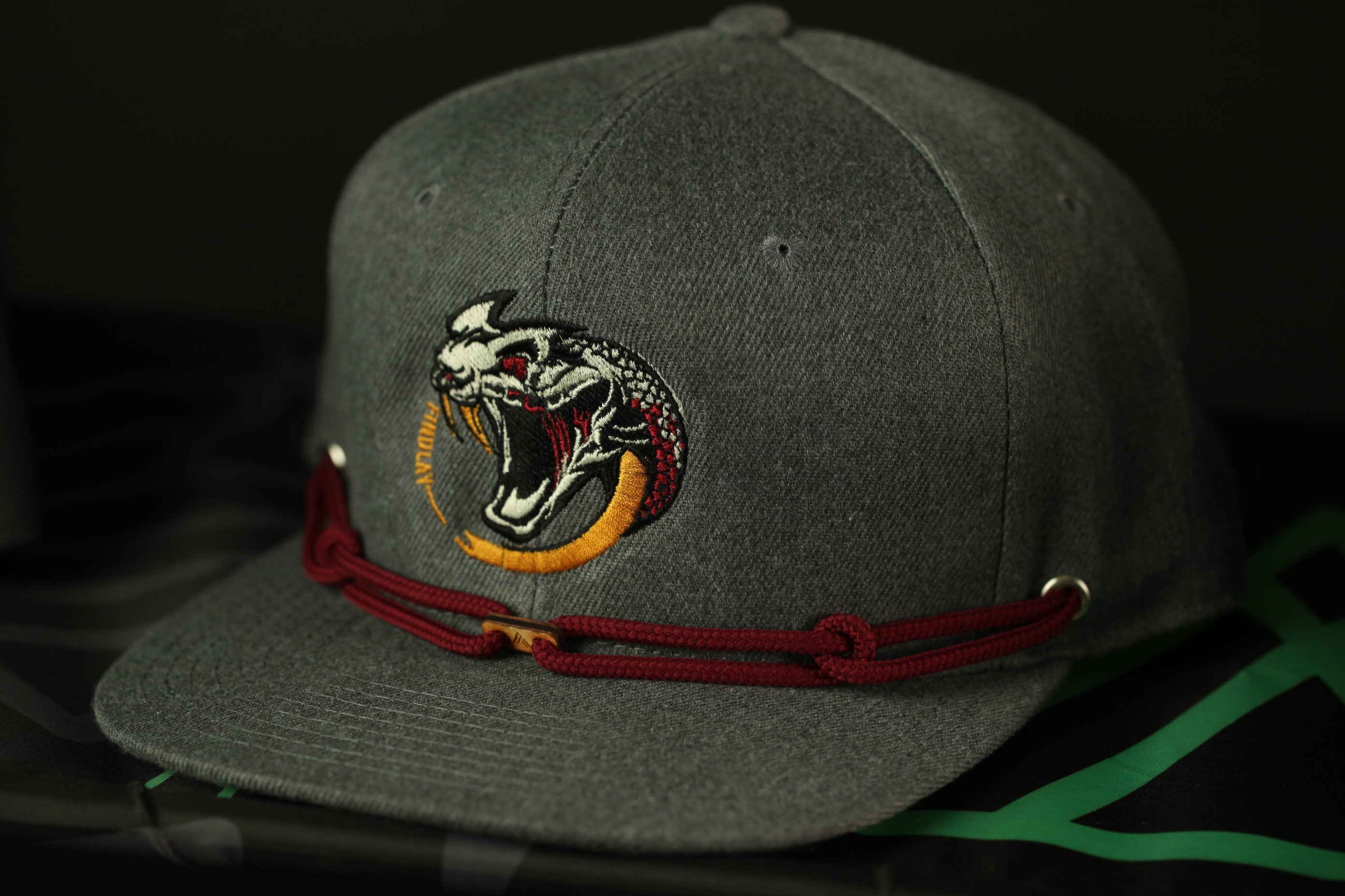 A gray baseball cap with a red and gold embroidered logo on the front.