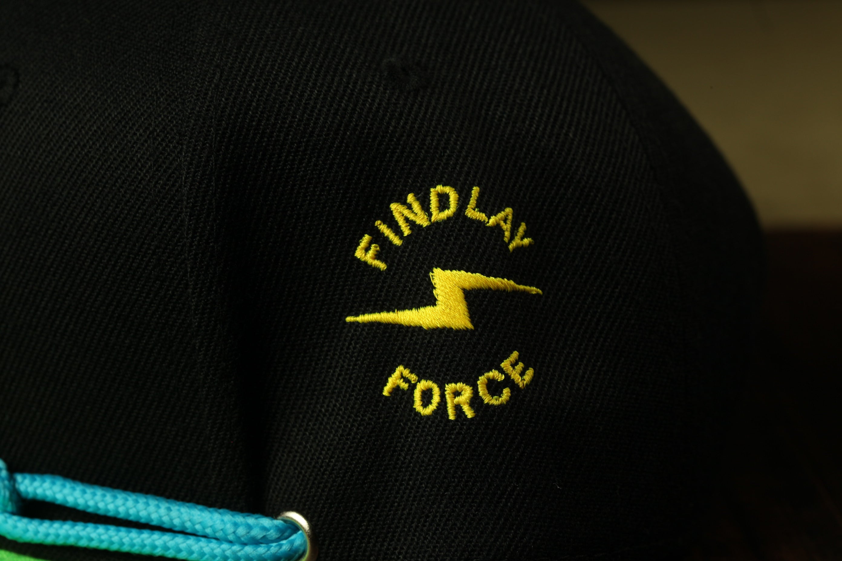 a close-up view of a black baseball cap with a yellow lightning bolt symbol and the text "FIND LAY FORCE" embroidered on it.