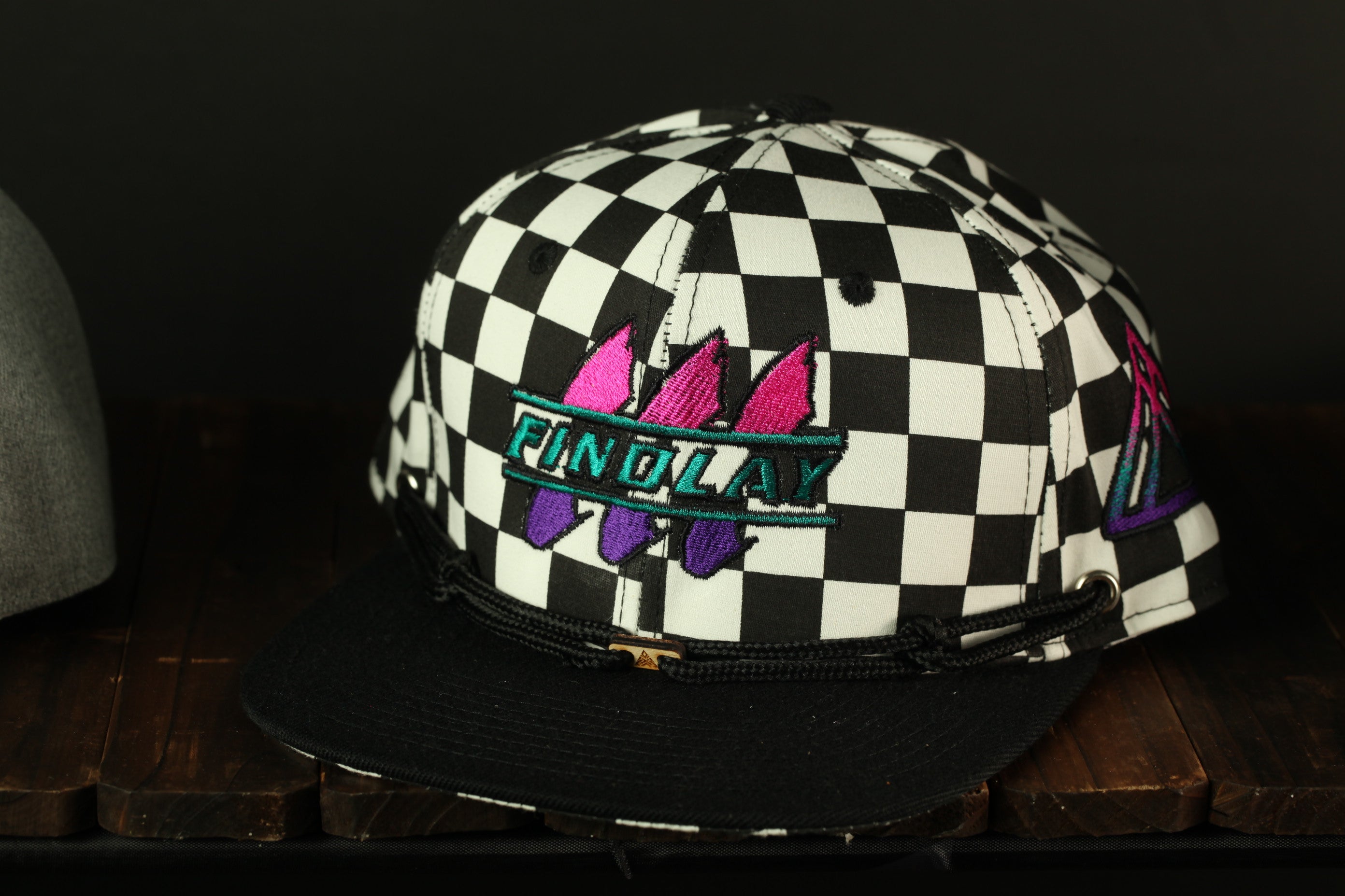 A black and white checkered baseball cap with a graphic design on the front.