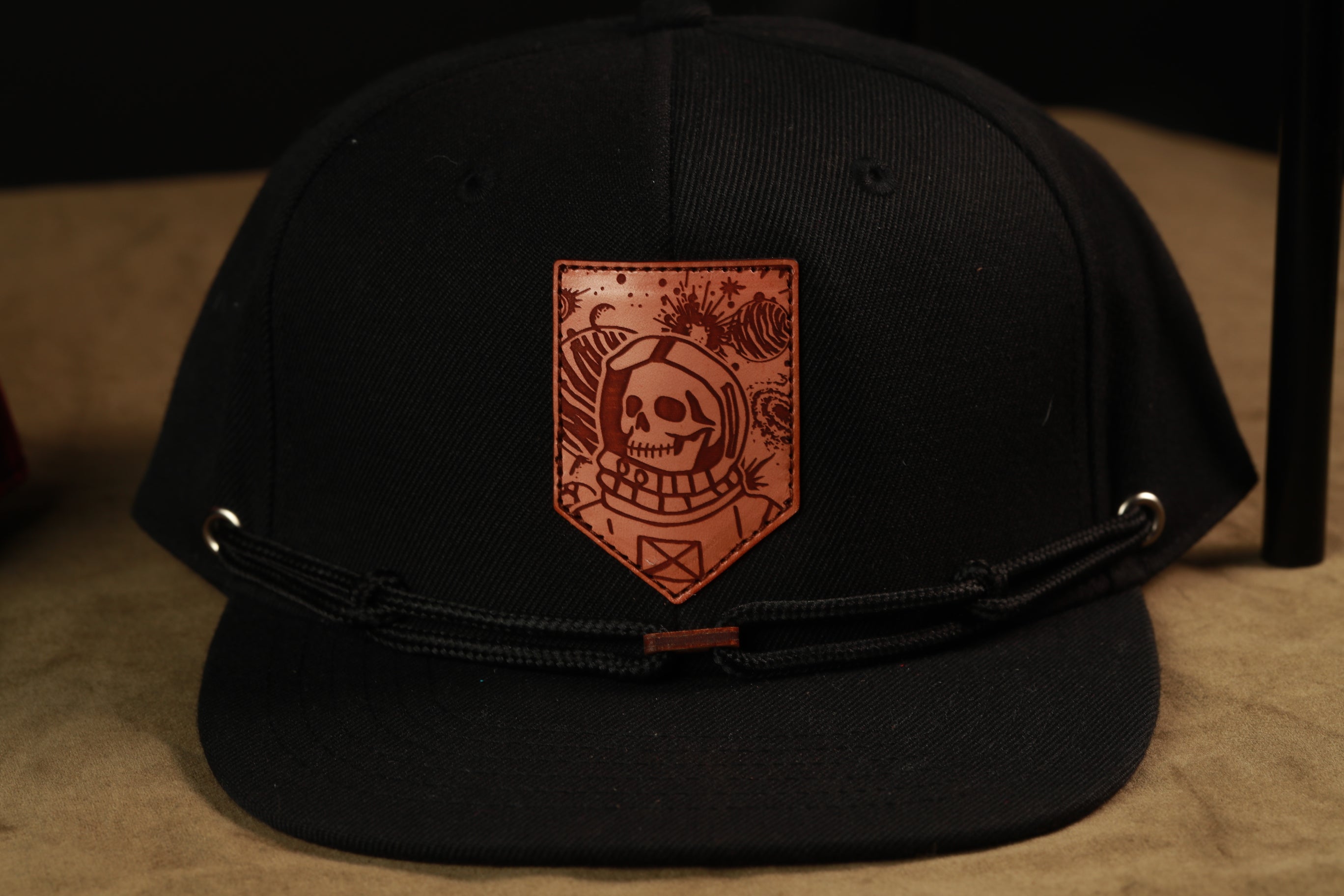 A black baseball cap with a leather patch featuring a skull and floral design.
