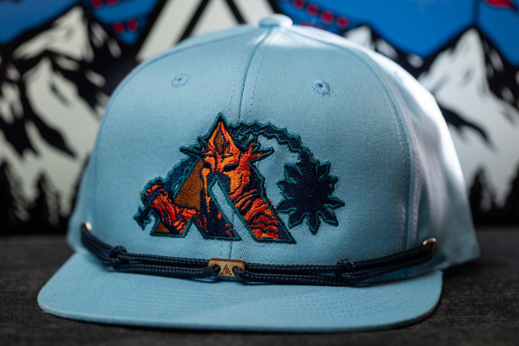 A light blue baseball cap with a colorful embroidered logo on the front.